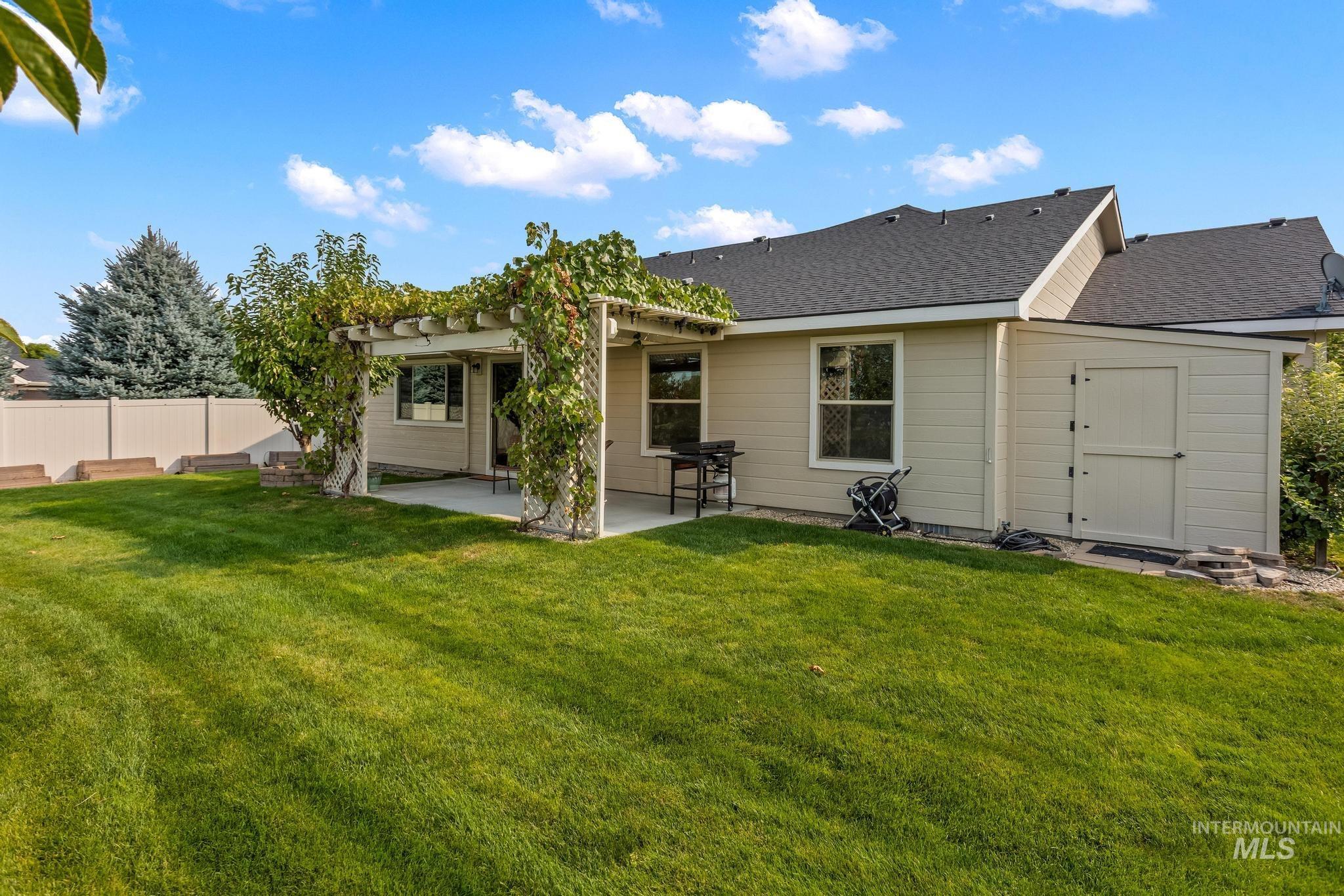 Rear view of property featuring a patio area, a storage shed, roof with shingles, and a pergola