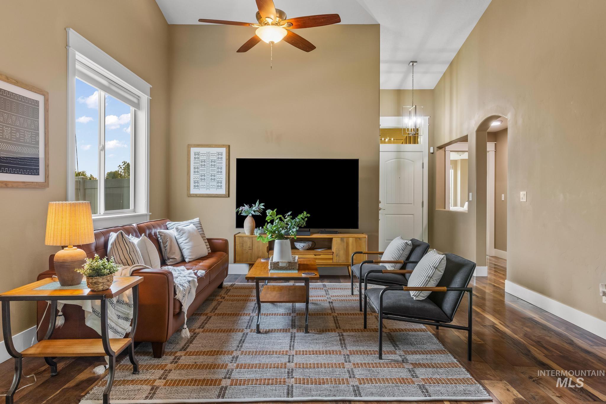 Living area with hardwood / wood-style floors, a ceiling fan, and a high ceiling