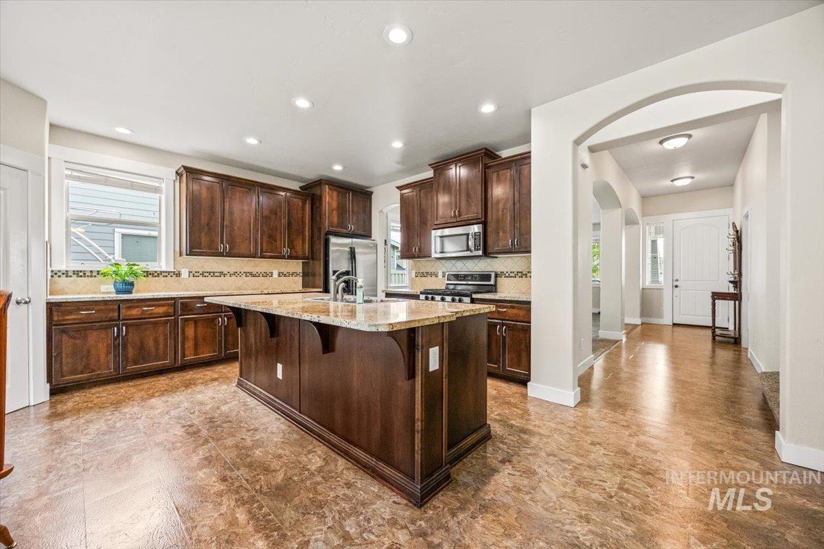 Kitchen with tasteful backsplash, arched walkways, a kitchen breakfast bar, plenty of natural light, and recessed lighting