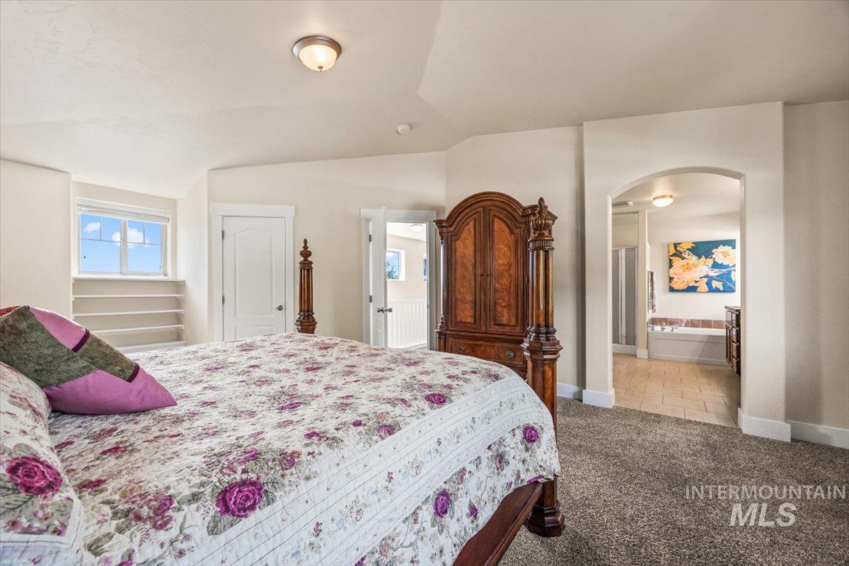 Bedroom featuring arched walkways, carpet, and vaulted ceiling