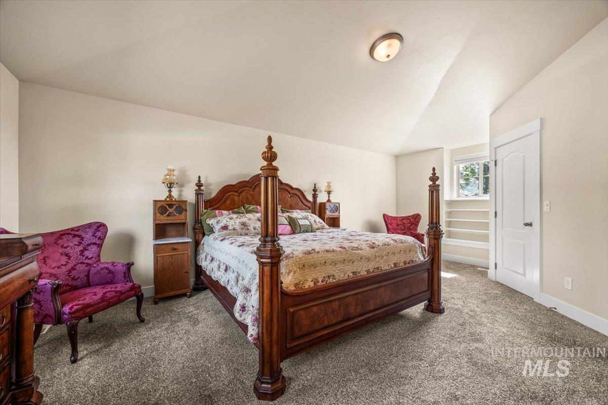 Carpeted bedroom with lofted ceiling and baseboards