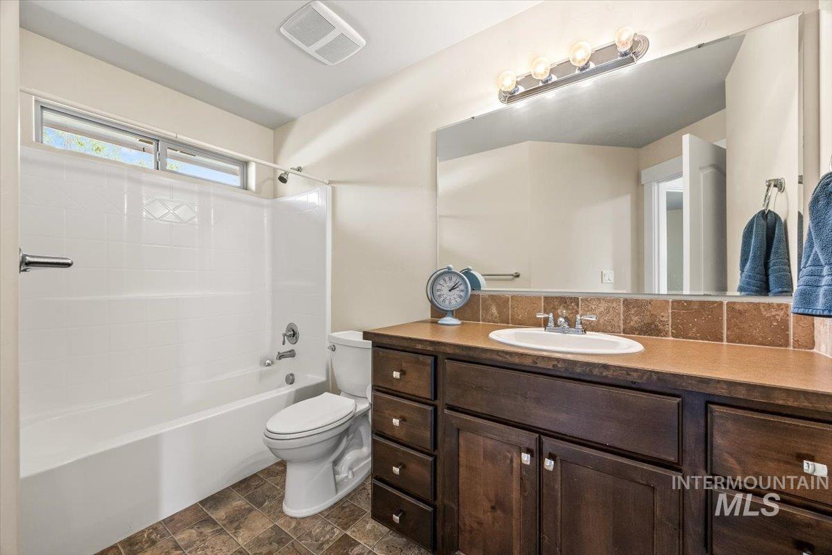 Bathroom featuring bathtub / shower combination, vanity, and stone finish flooring