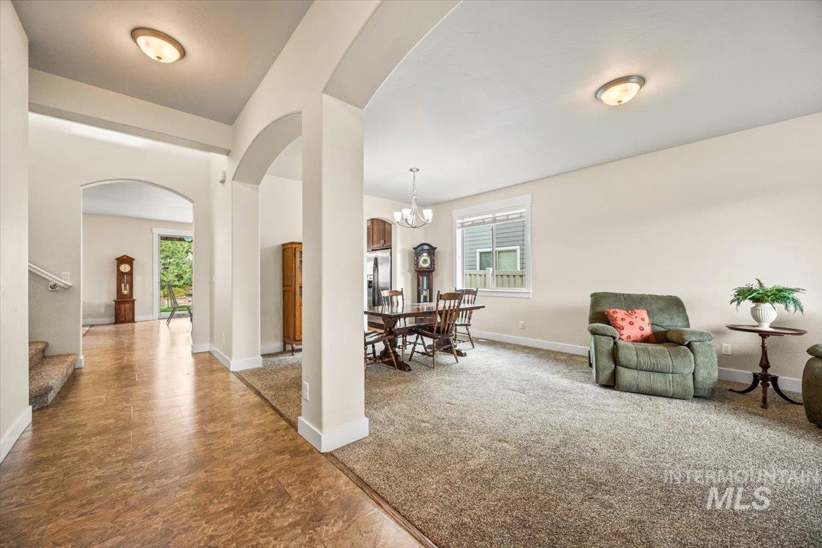 Dining room with arched walkways, stairs, a chandelier, and carpet floors