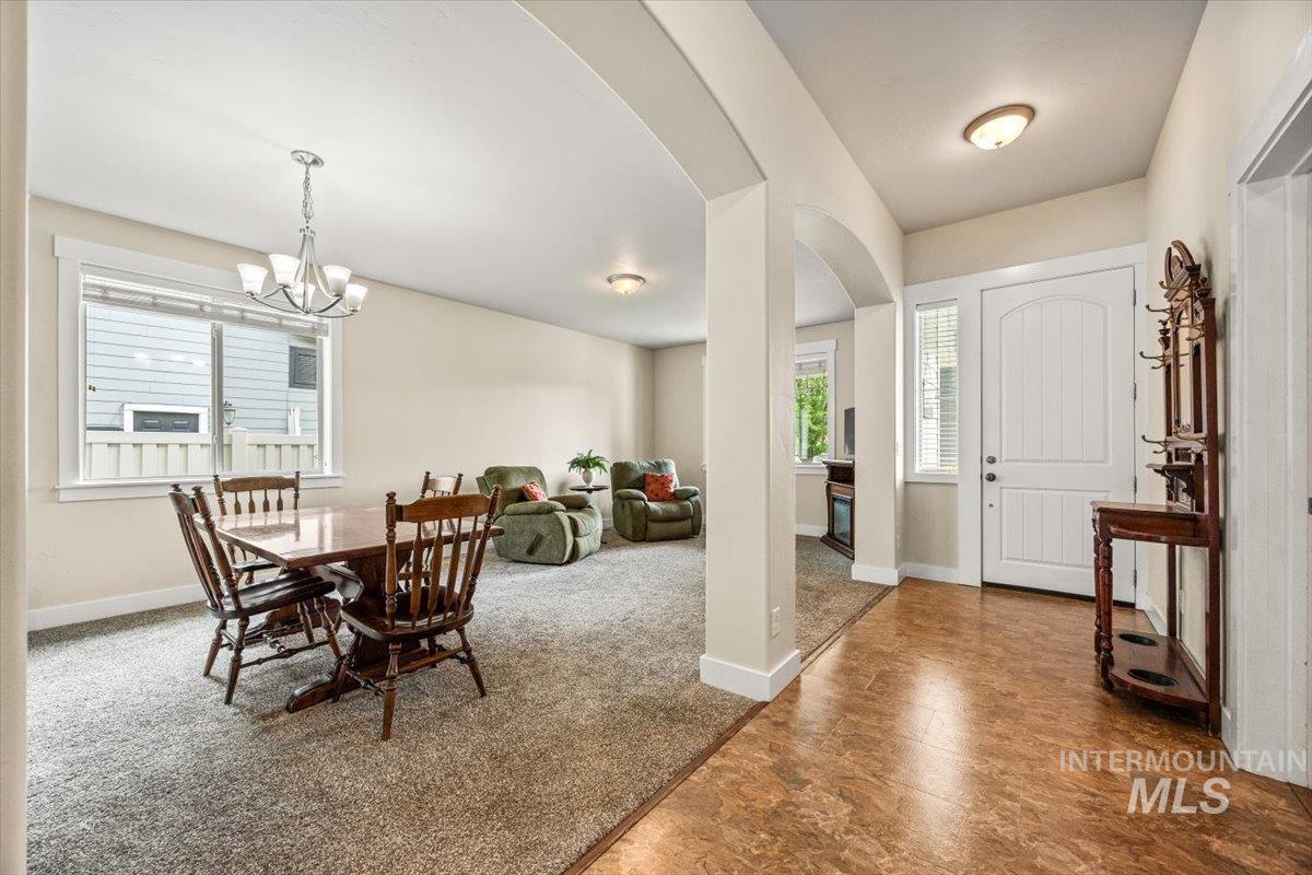 Carpeted dining area with arched walkways and a chandelier