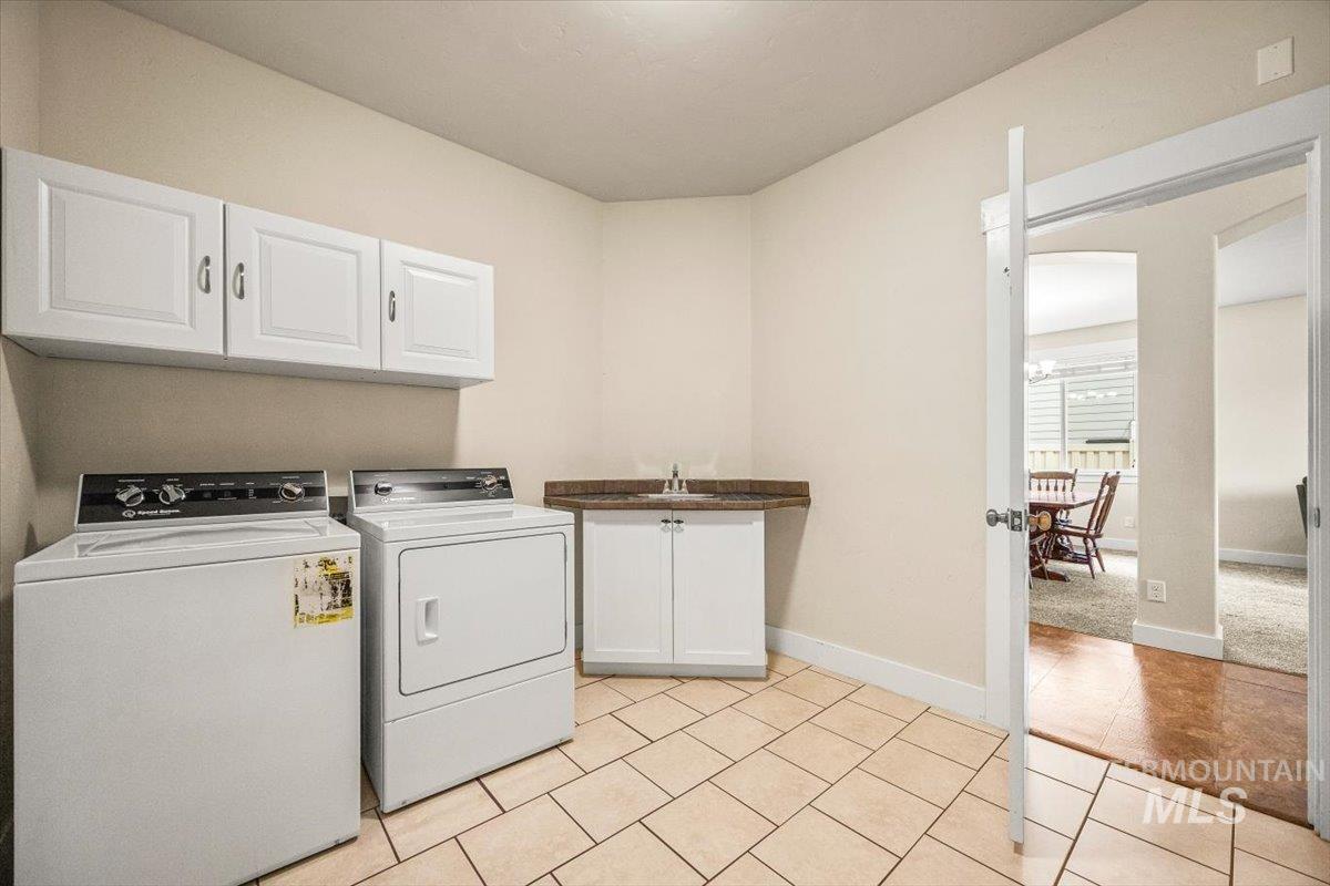 Laundry area featuring cabinet space, light tile patterned flooring, and washer and clothes dryer