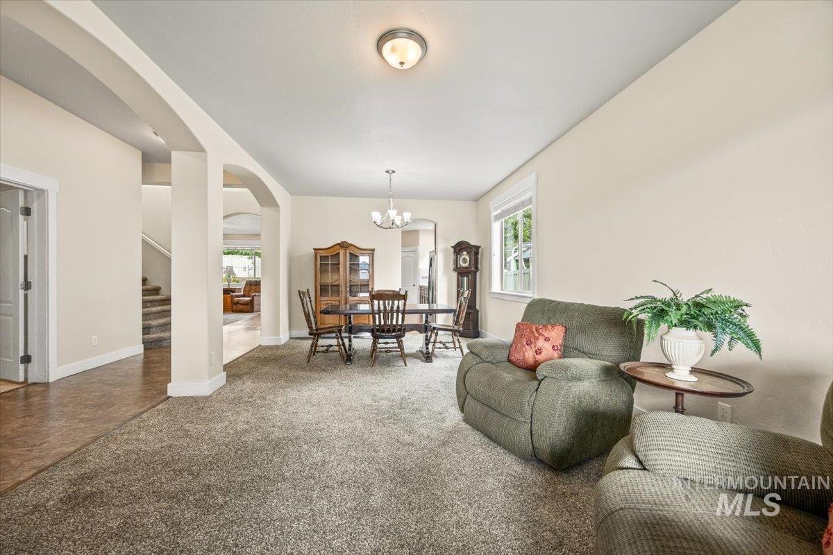 Carpeted living area featuring arched walkways, stairs, and a chandelier