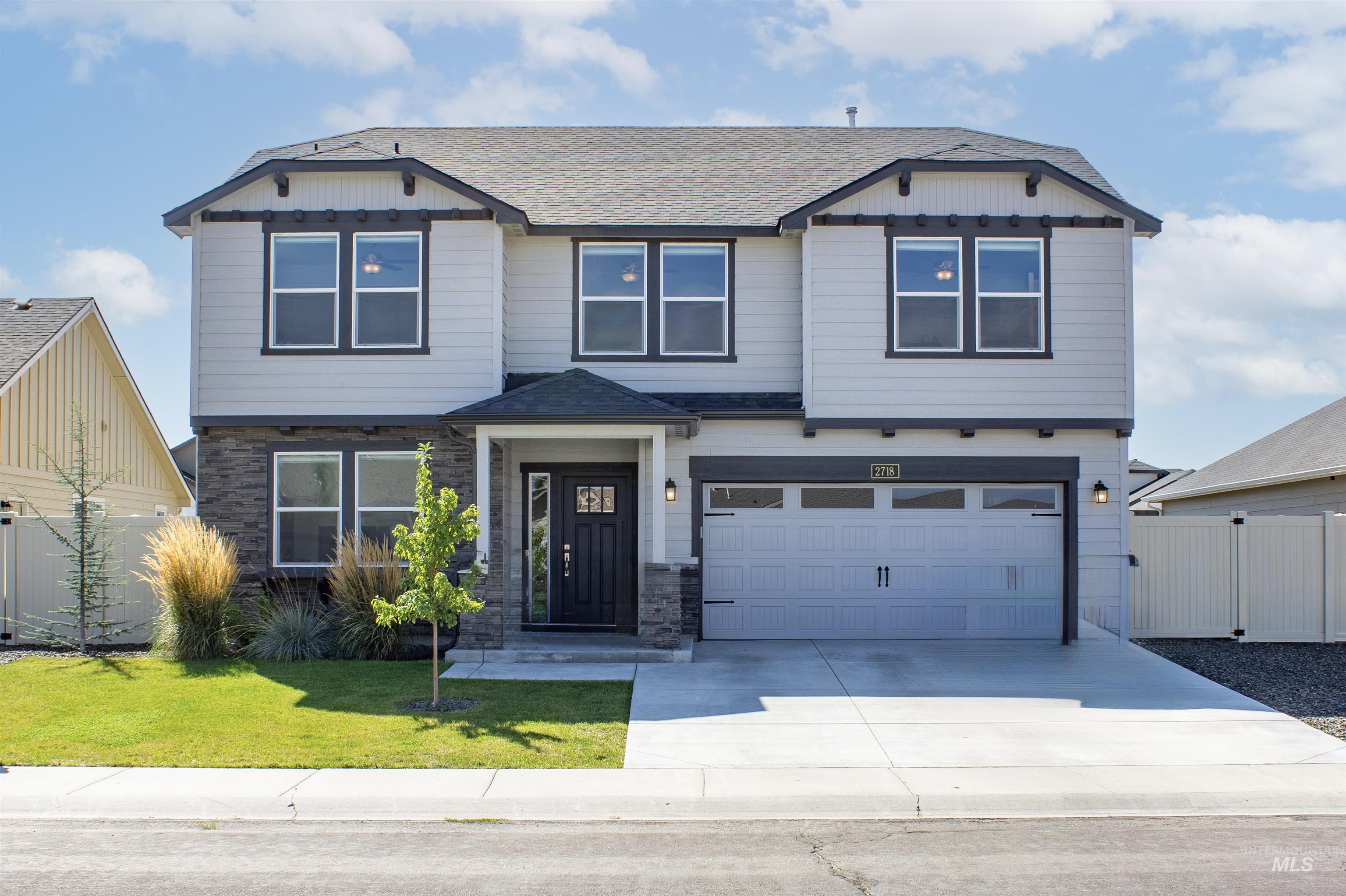Craftsman-style house with stone siding, driveway, roof with shingles, and a garage