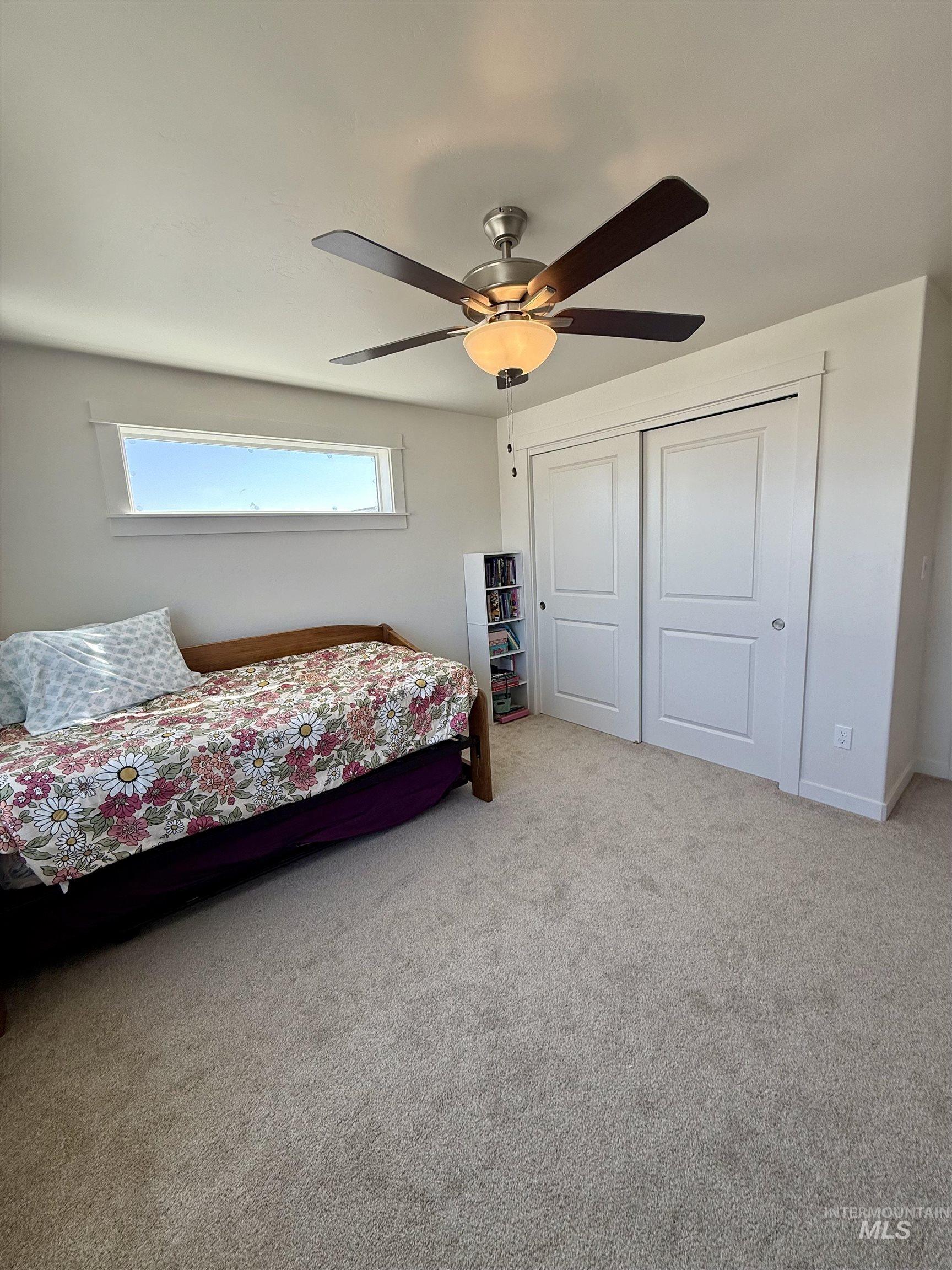Carpeted bedroom featuring a ceiling fan and a closet