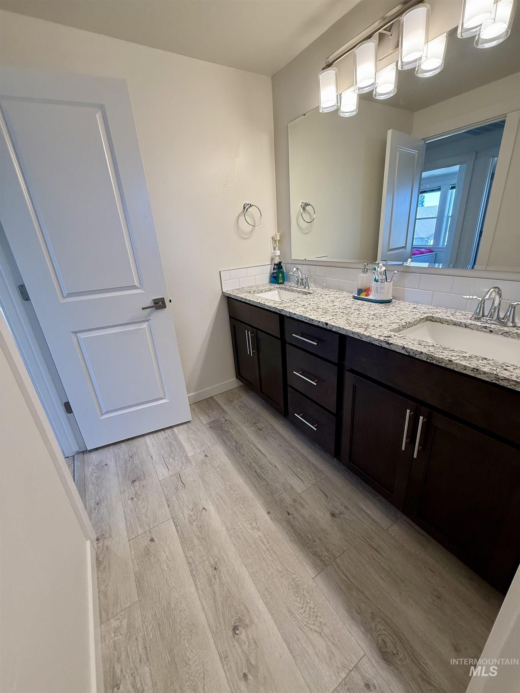 Full bathroom with light wood-type flooring and double vanity
