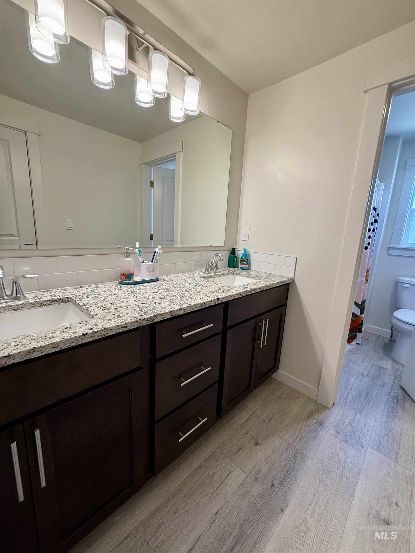 Bathroom featuring double vanity and light wood finished floors