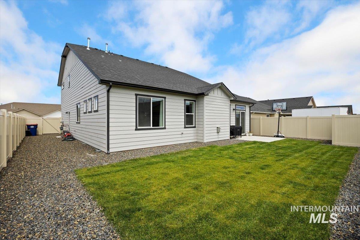 Back of property featuring a patio, a fenced backyard, and roof with shingles