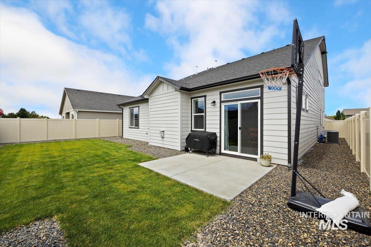 Rear view of house featuring a fenced backyard, a patio, heating fuel, and board and batten siding