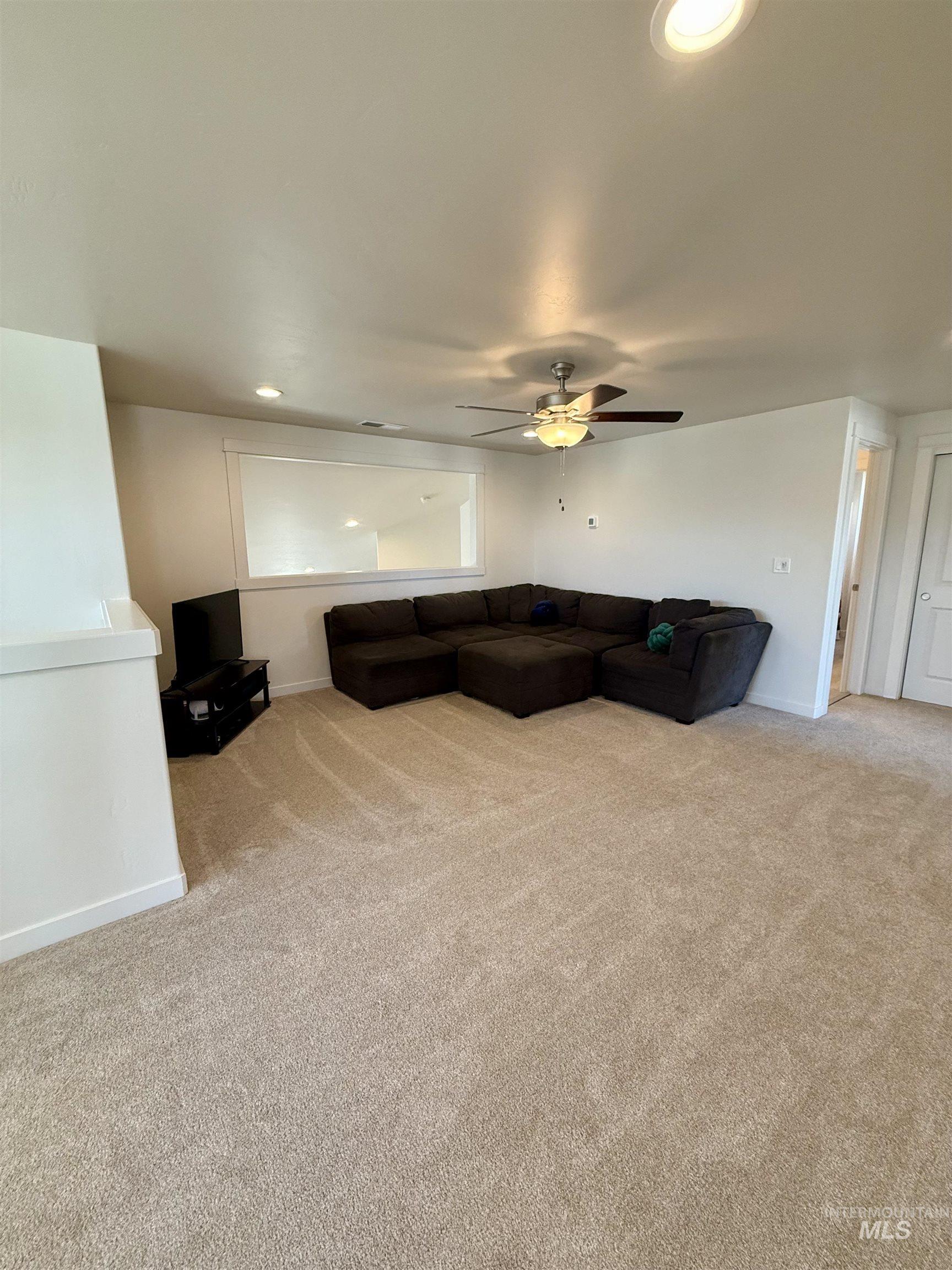 Living area with light colored carpet, recessed lighting, and ceiling fan