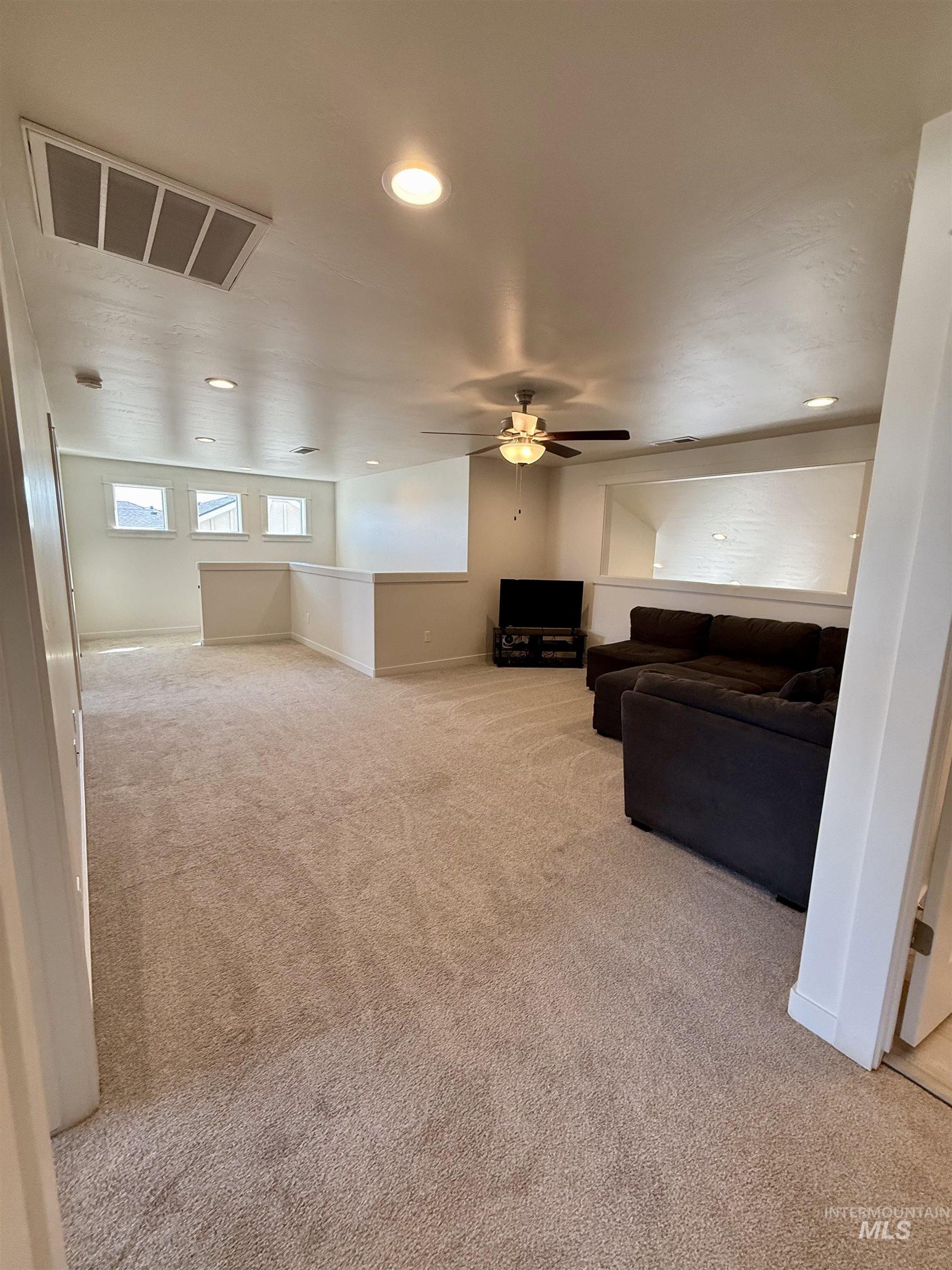 Living area with light carpet and recessed lighting