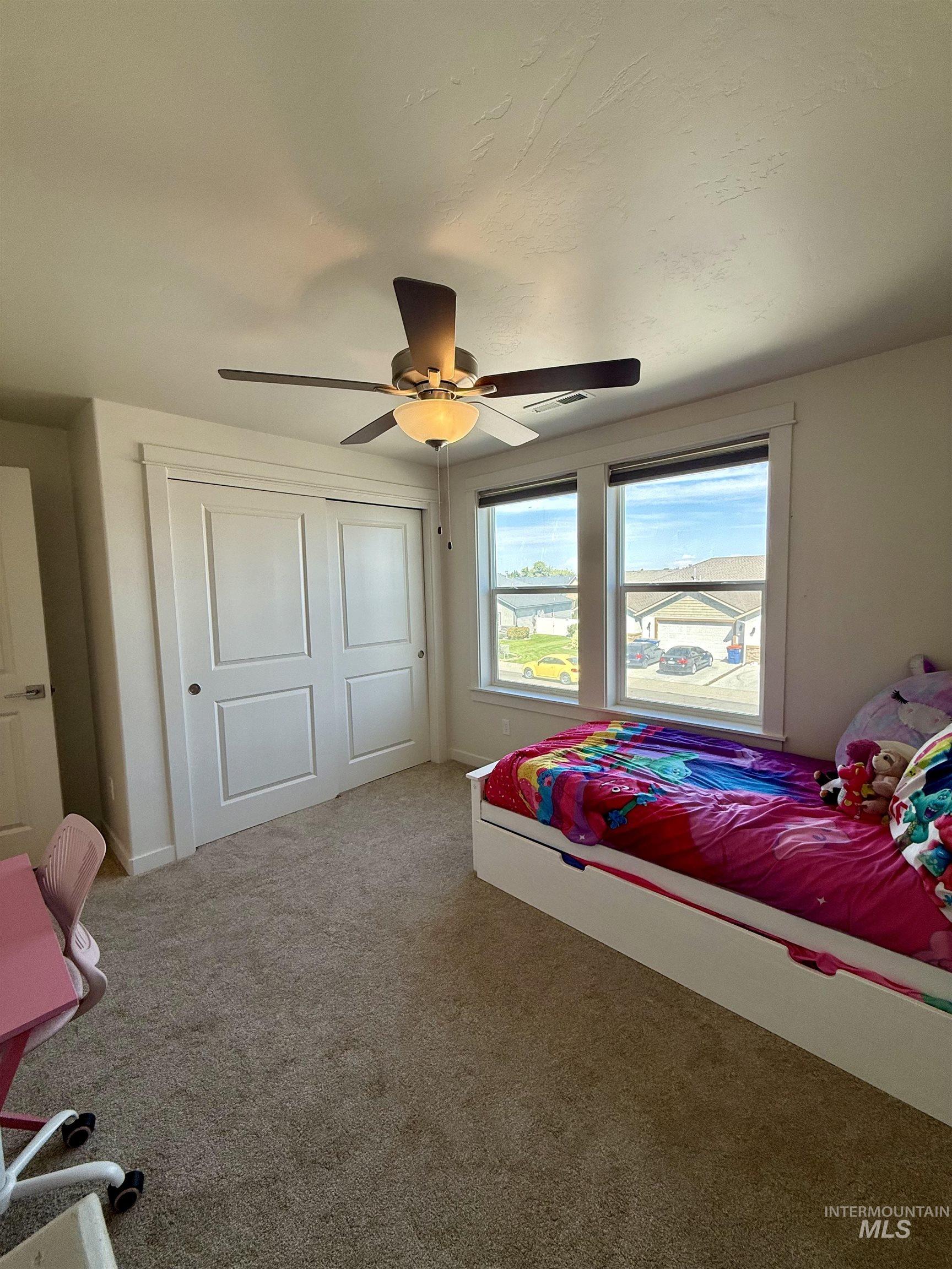 Carpeted bedroom with a ceiling fan and a closet