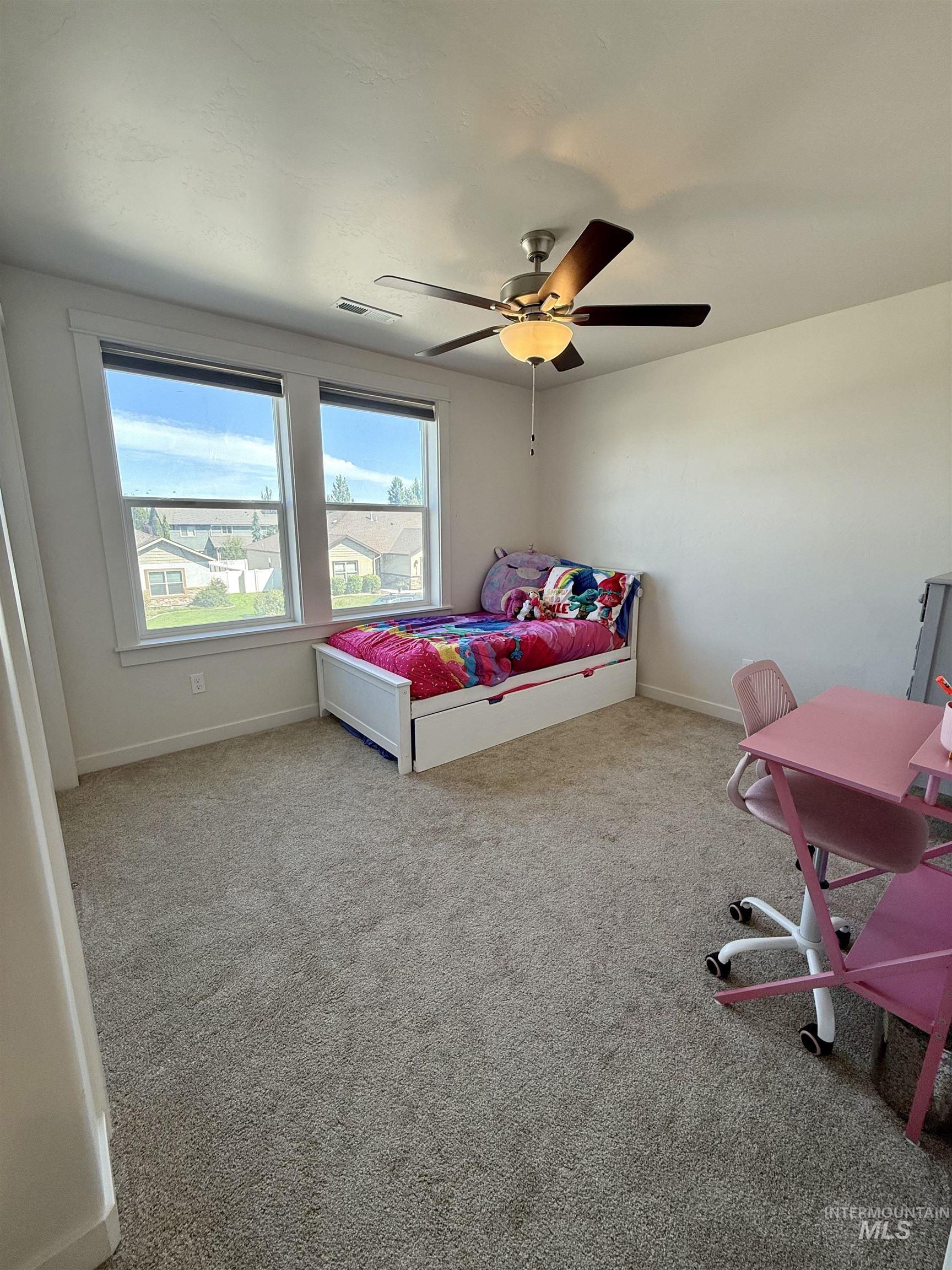 Carpeted bedroom with a ceiling fan and an office area