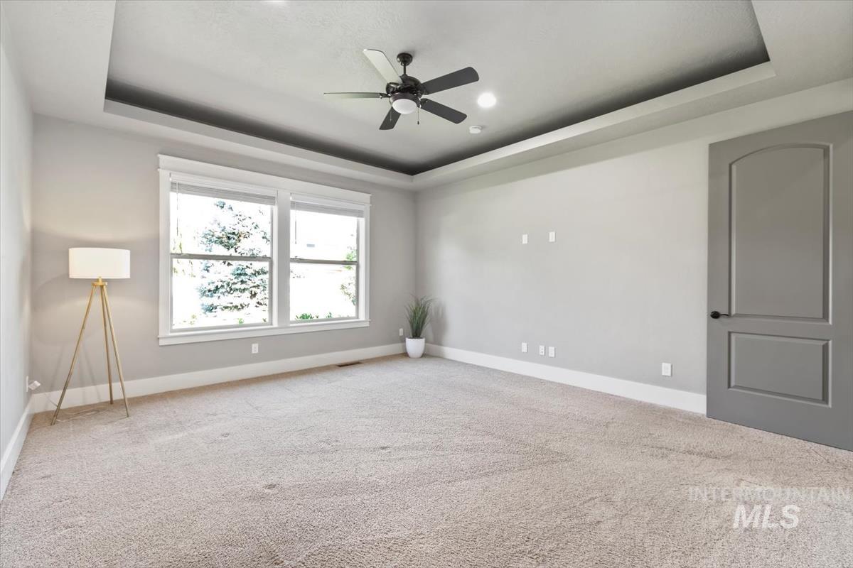 Unfurnished room with a raised ceiling, carpet, ceiling fan, and recessed lighting