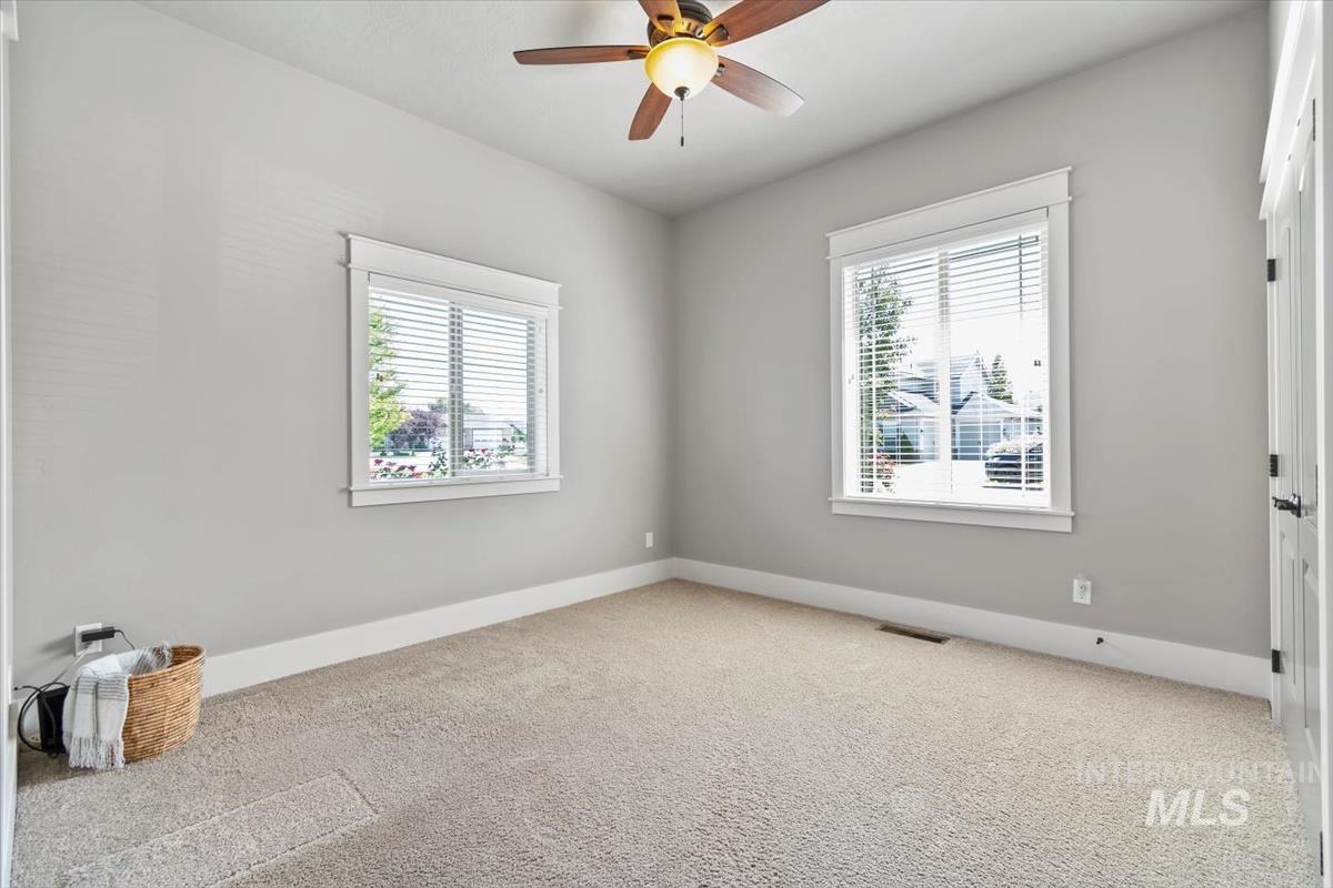 Second bedroom. Carpeted empty room featuring baseboards and a ceiling fan