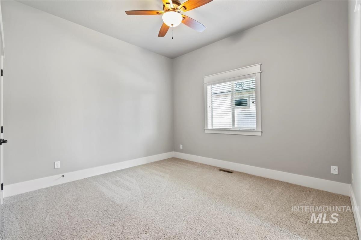 Carpeted empty room with baseboards and ceiling fan