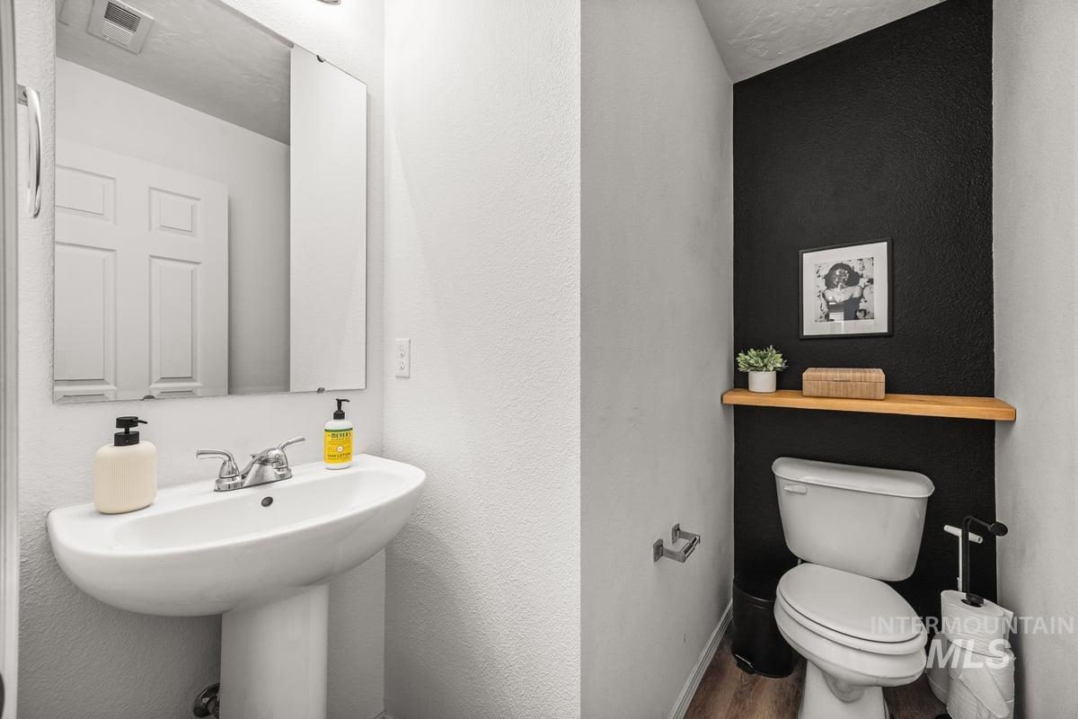 Half bathroom with a textured wall and wood finished floors