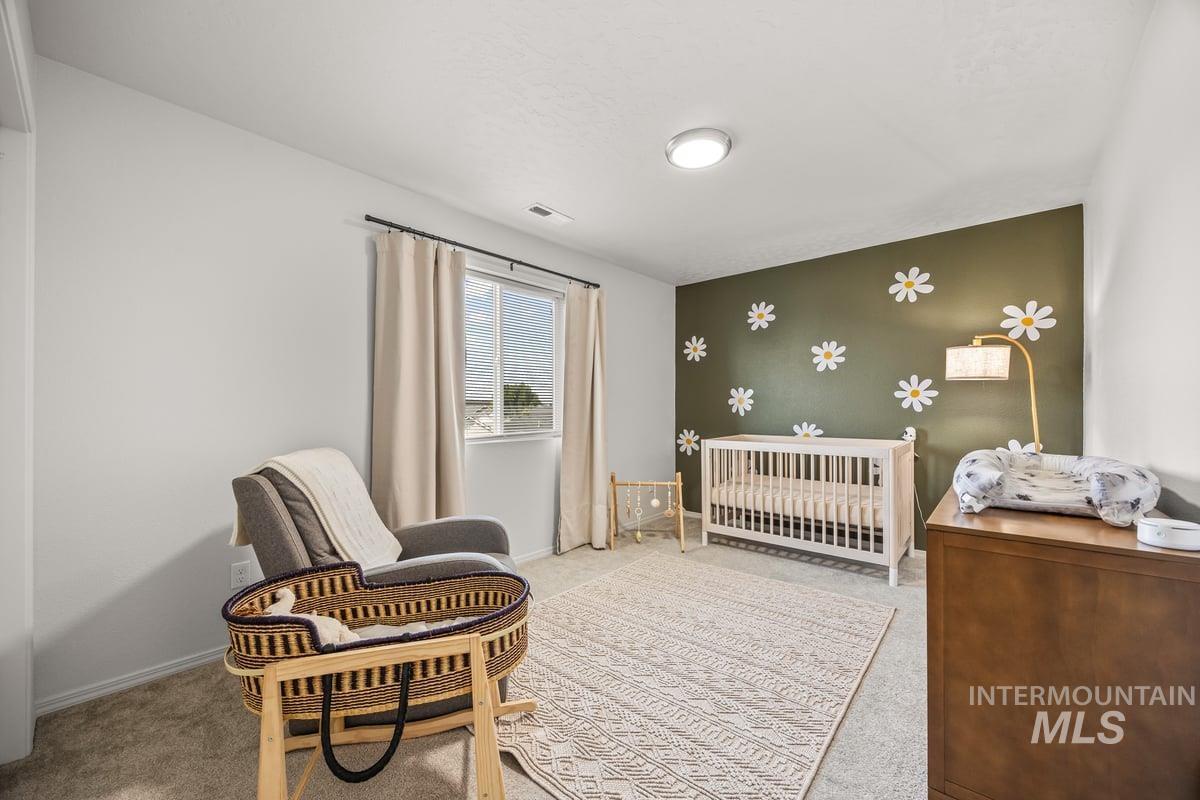 Carpeted bedroom with a nursery area and baseboards