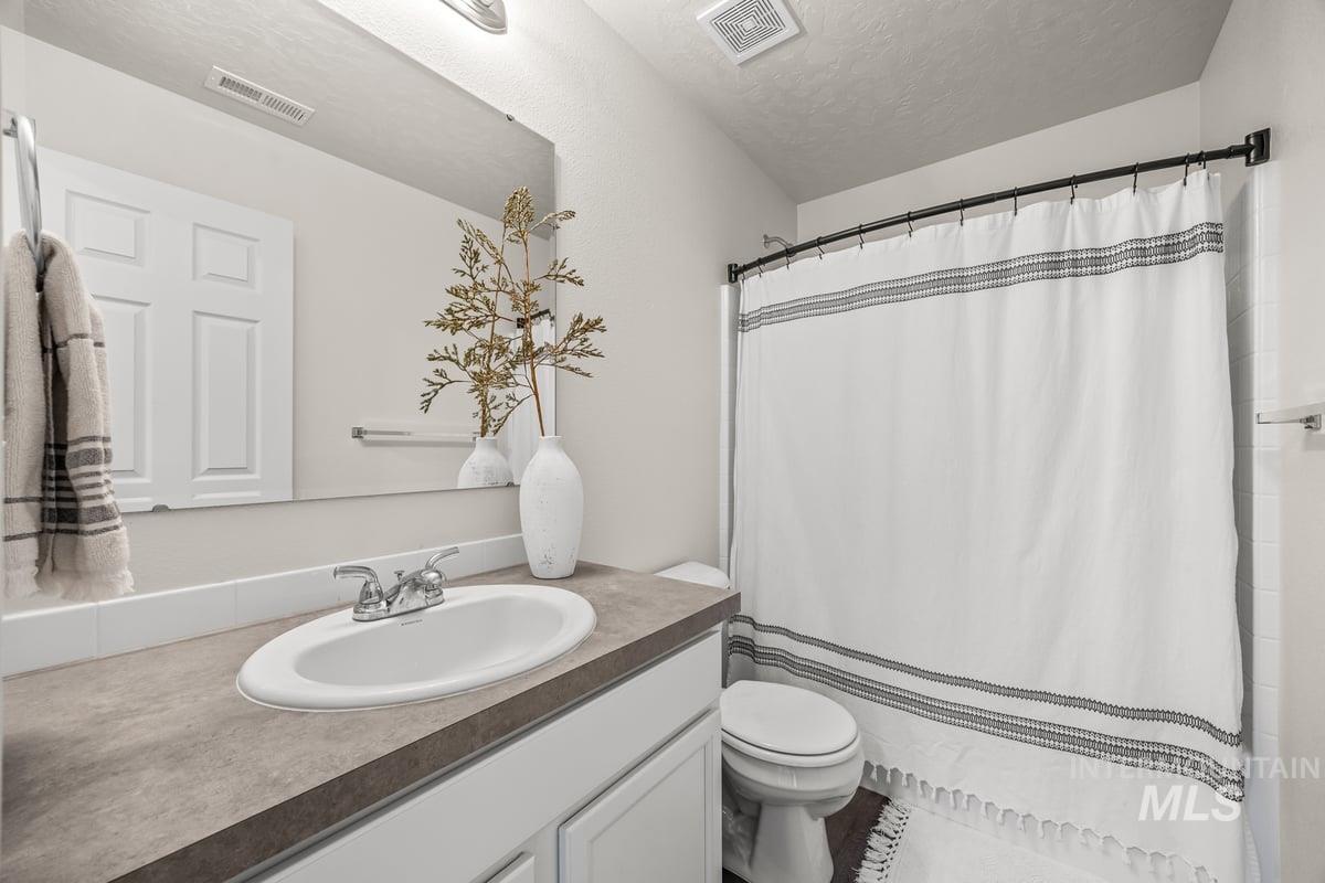 Full bathroom featuring vanity, a textured ceiling, and a shower with shower curtain