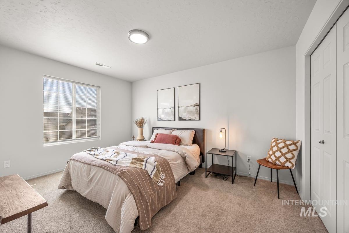 Bedroom featuring light colored carpet, a closet, and a textured ceiling