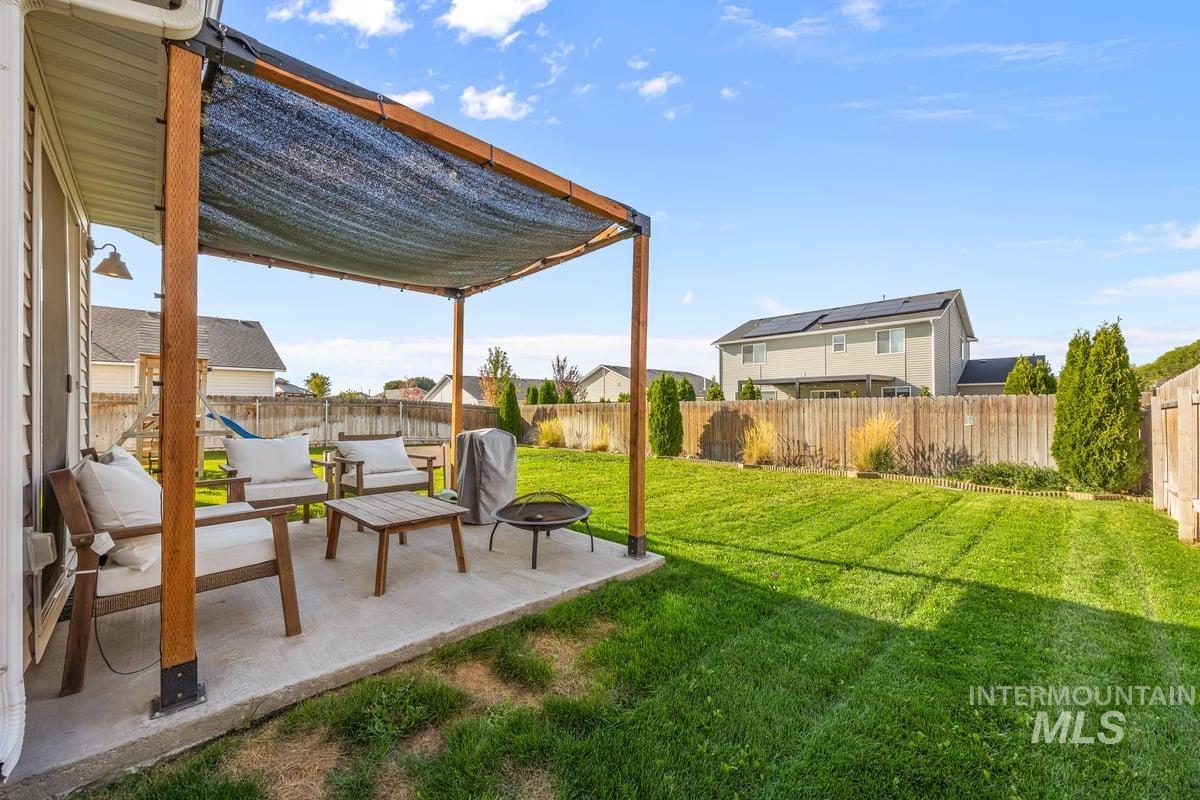 Fenced backyard with a patio area and an outdoor living space with a fire pit