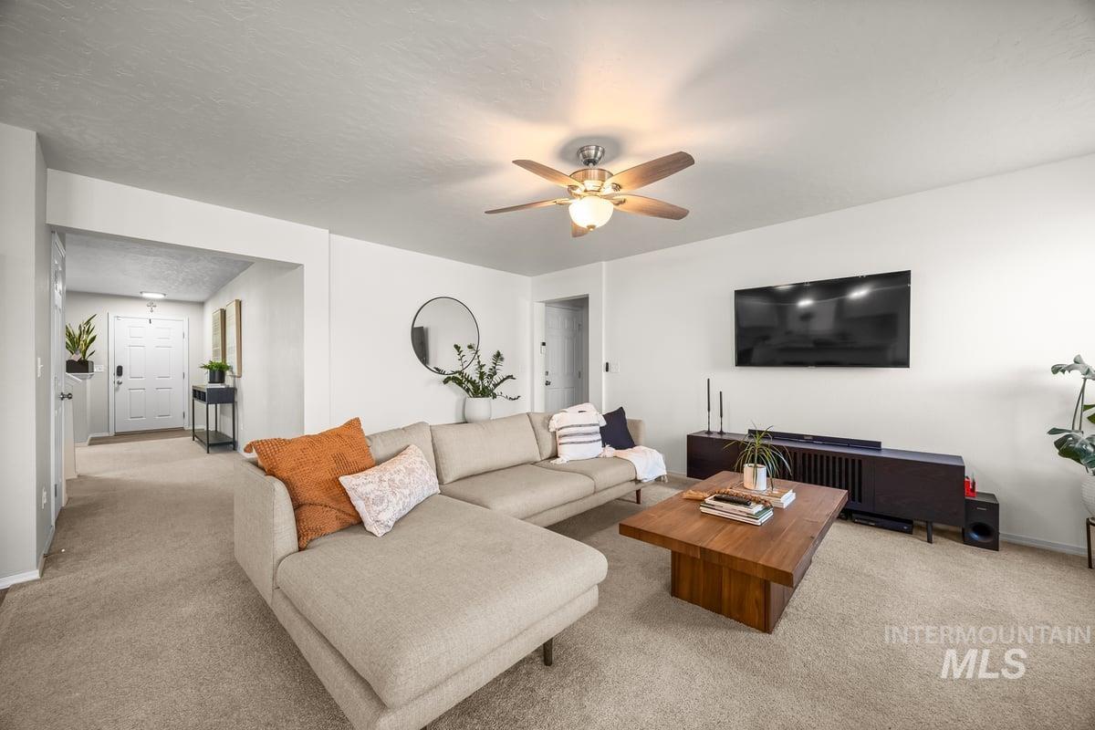 Carpeted living area with a ceiling fan and a textured ceiling