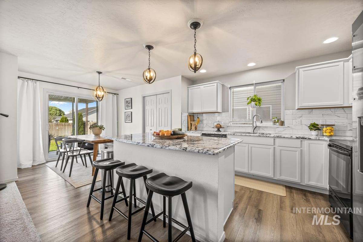 Kitchen with backsplash, light stone countertops, a kitchen breakfast bar, decorative light fixtures, and recessed lighting