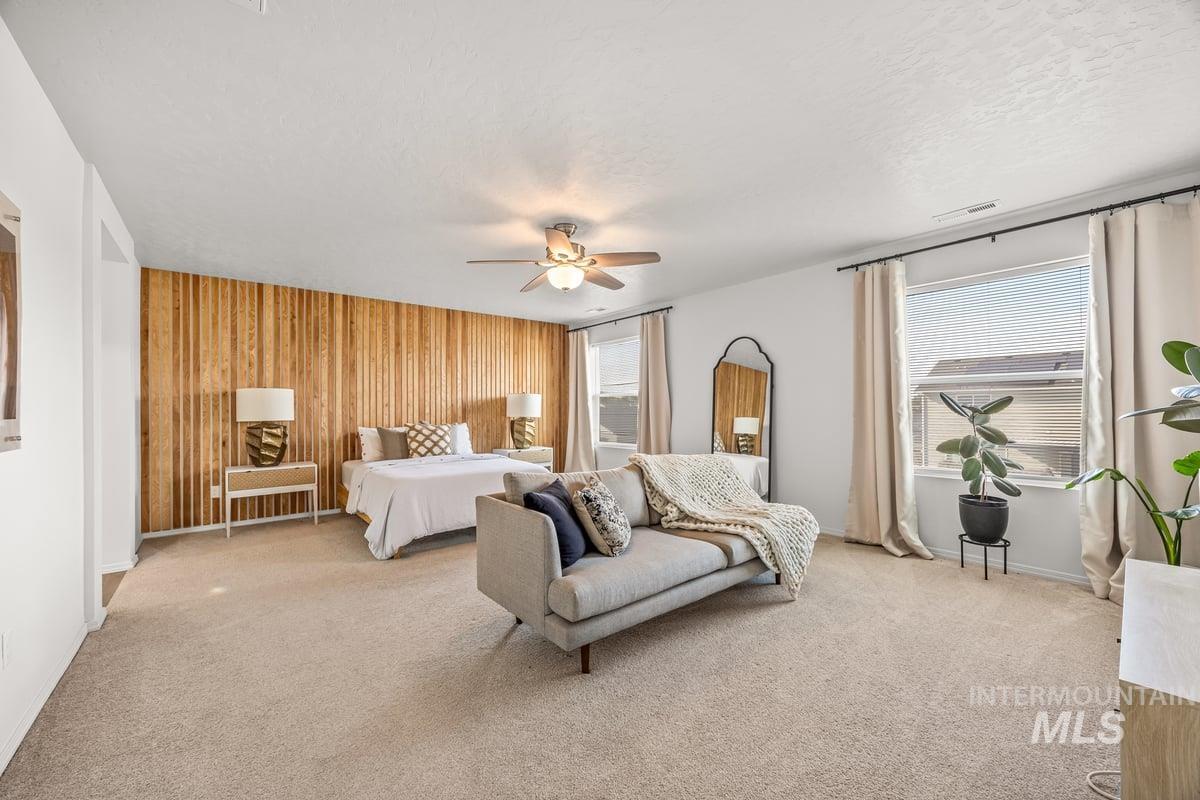Carpeted bedroom featuring wooden walls, a ceiling fan, and a textured ceiling