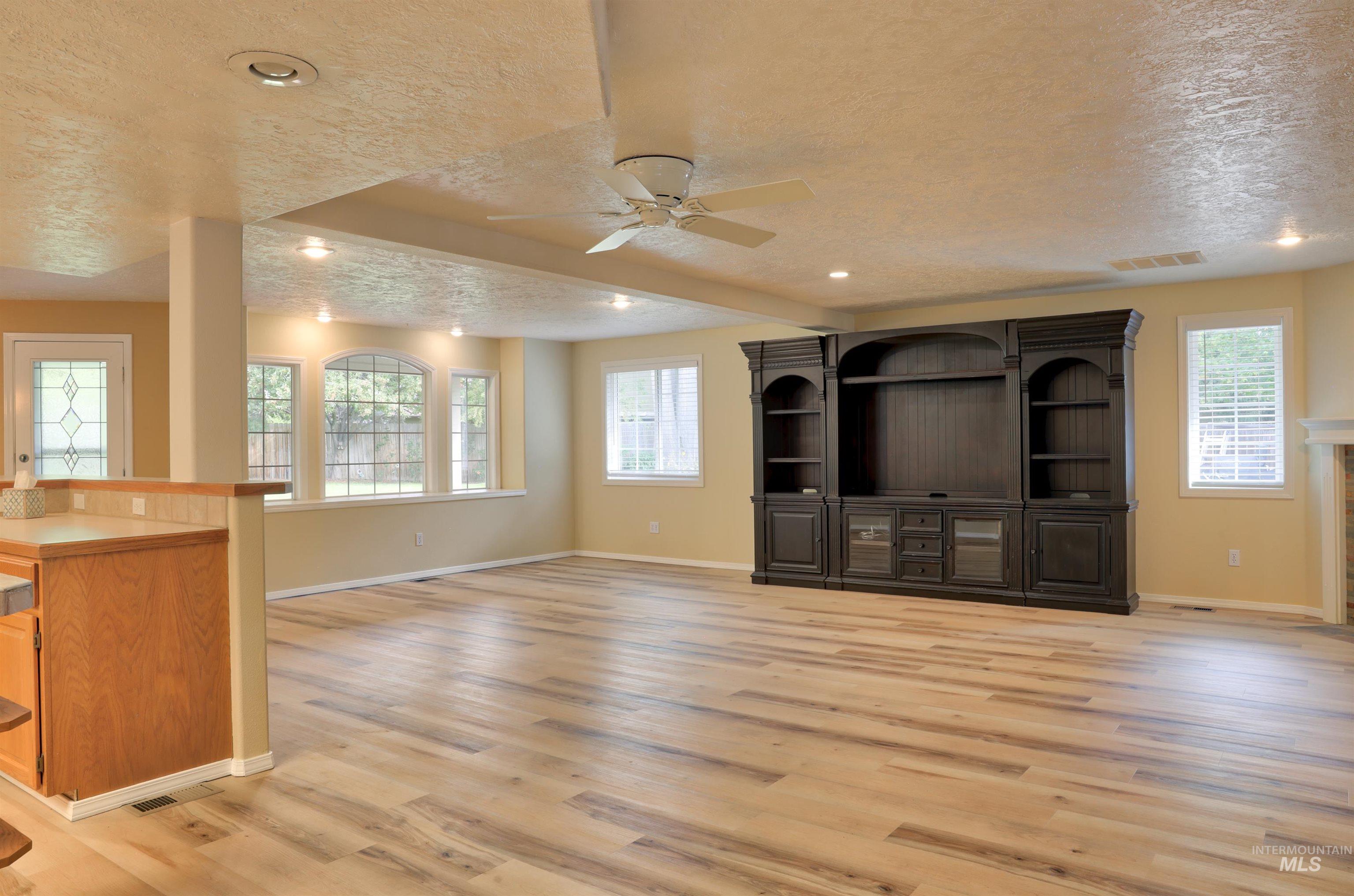 Unfurnished living room with a textured ceiling, light wood-type flooring, ceiling fan, and recessed lighting