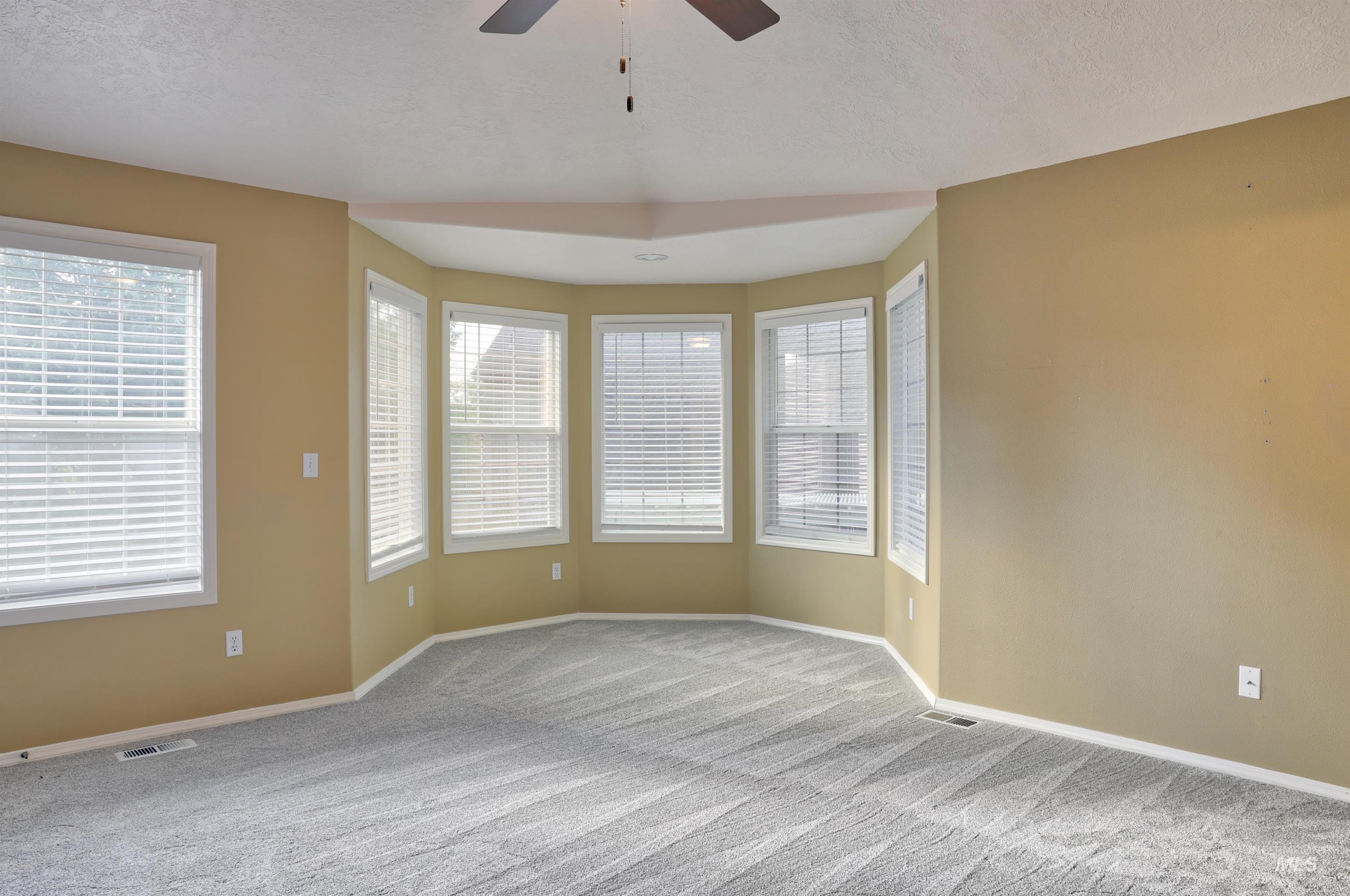 Unfurnished room featuring carpet, plenty of natural light, a textured ceiling, and ceiling fan