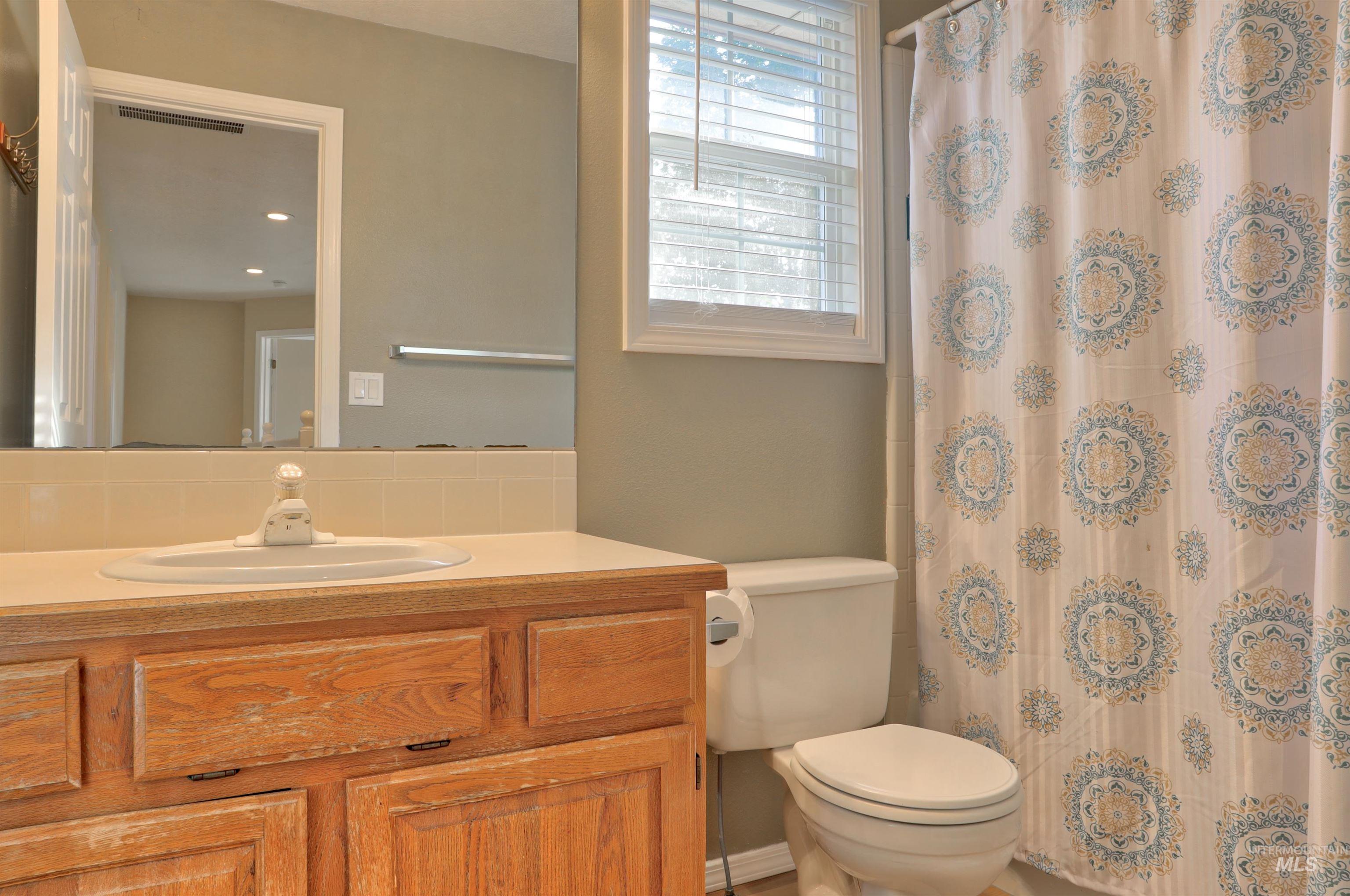 Bathroom with vanity, curtained shower, and decorative backsplash