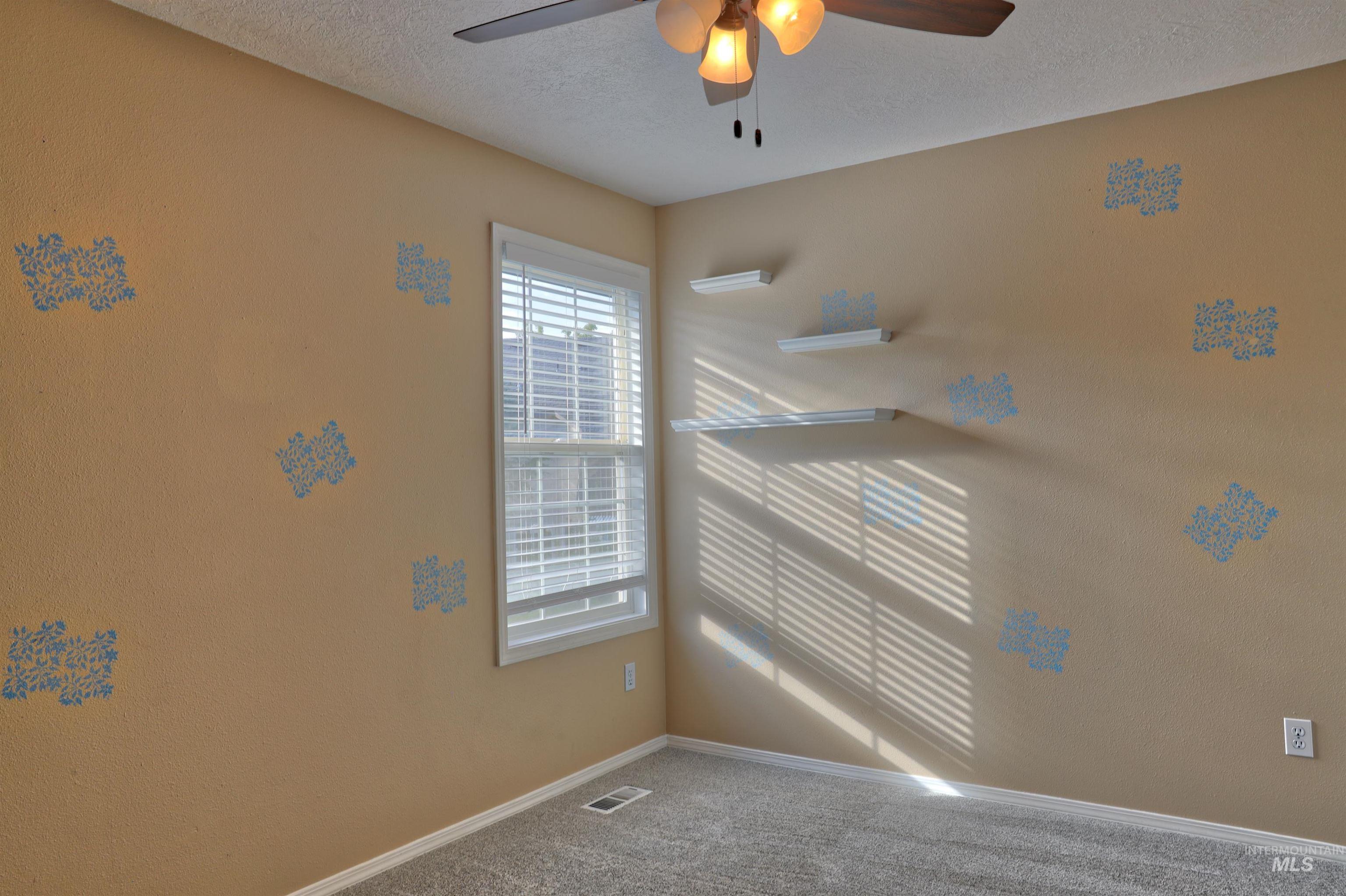 Spare room featuring carpet flooring, a textured ceiling, and ceiling fan