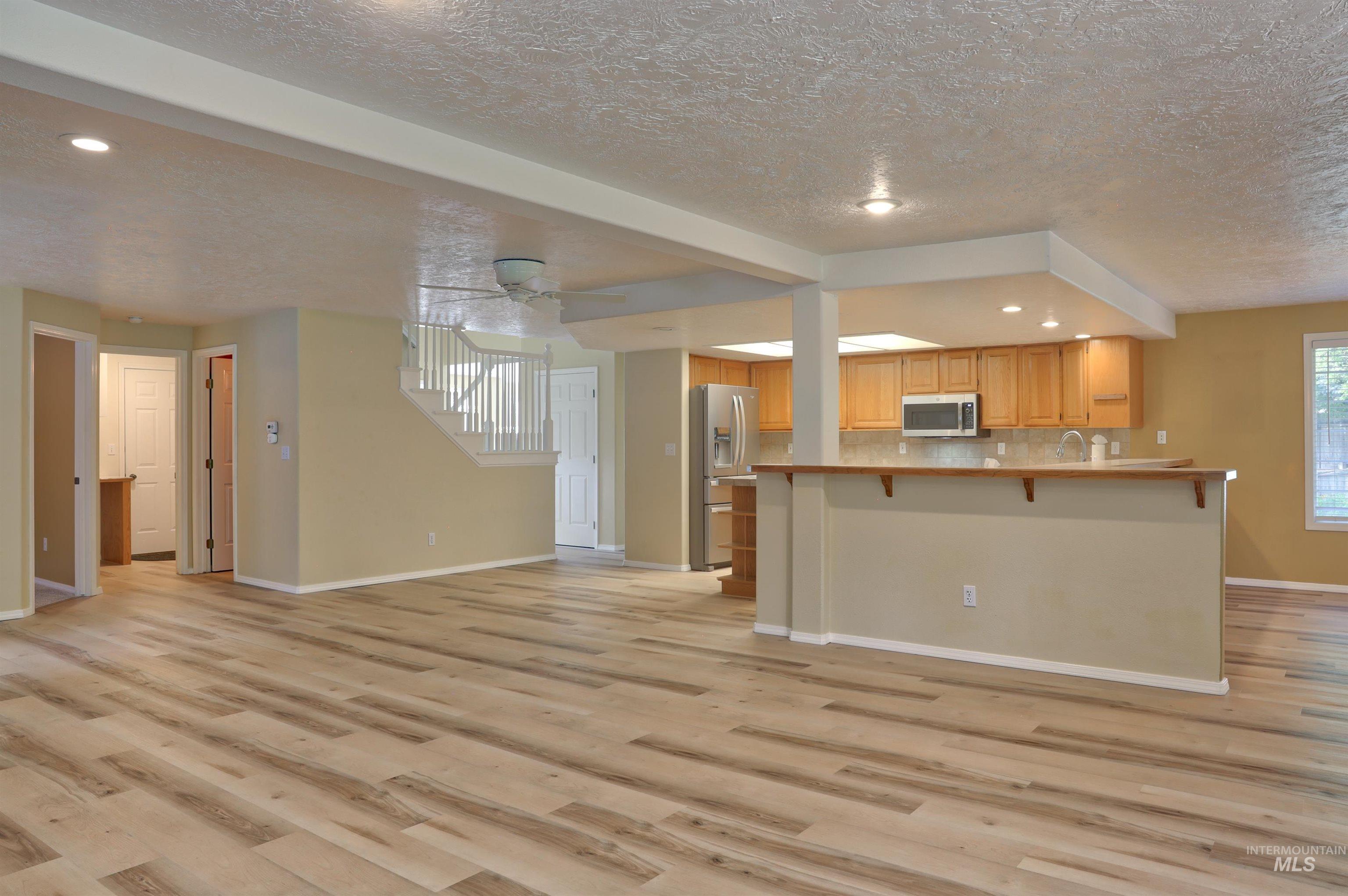 Kitchen featuring a breakfast bar area, open floor plan, a ceiling fan, recessed lighting, and light wood-type flooring
