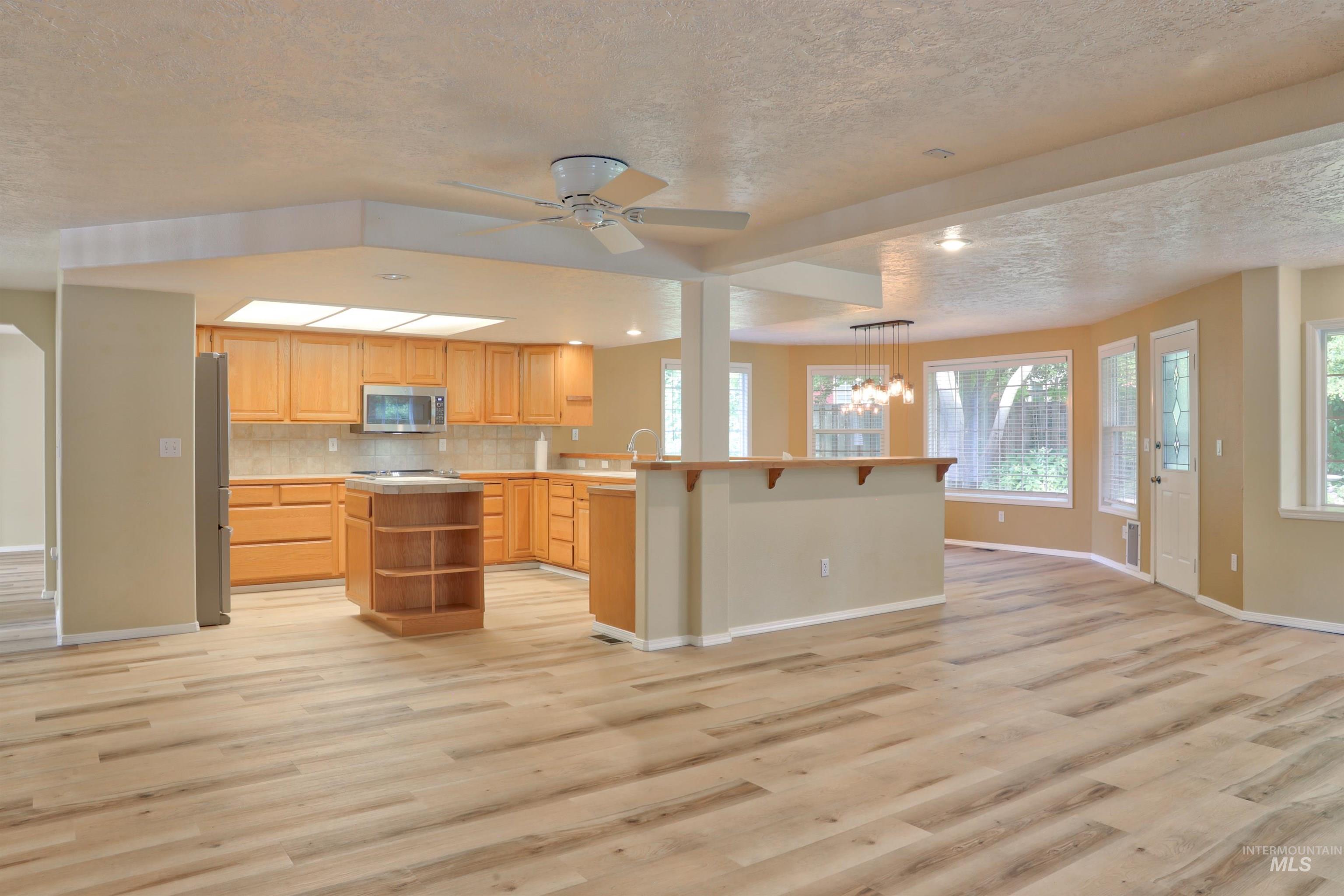 Kitchen with a textured ceiling, light countertops, plenty of natural light, and light wood-type flooring