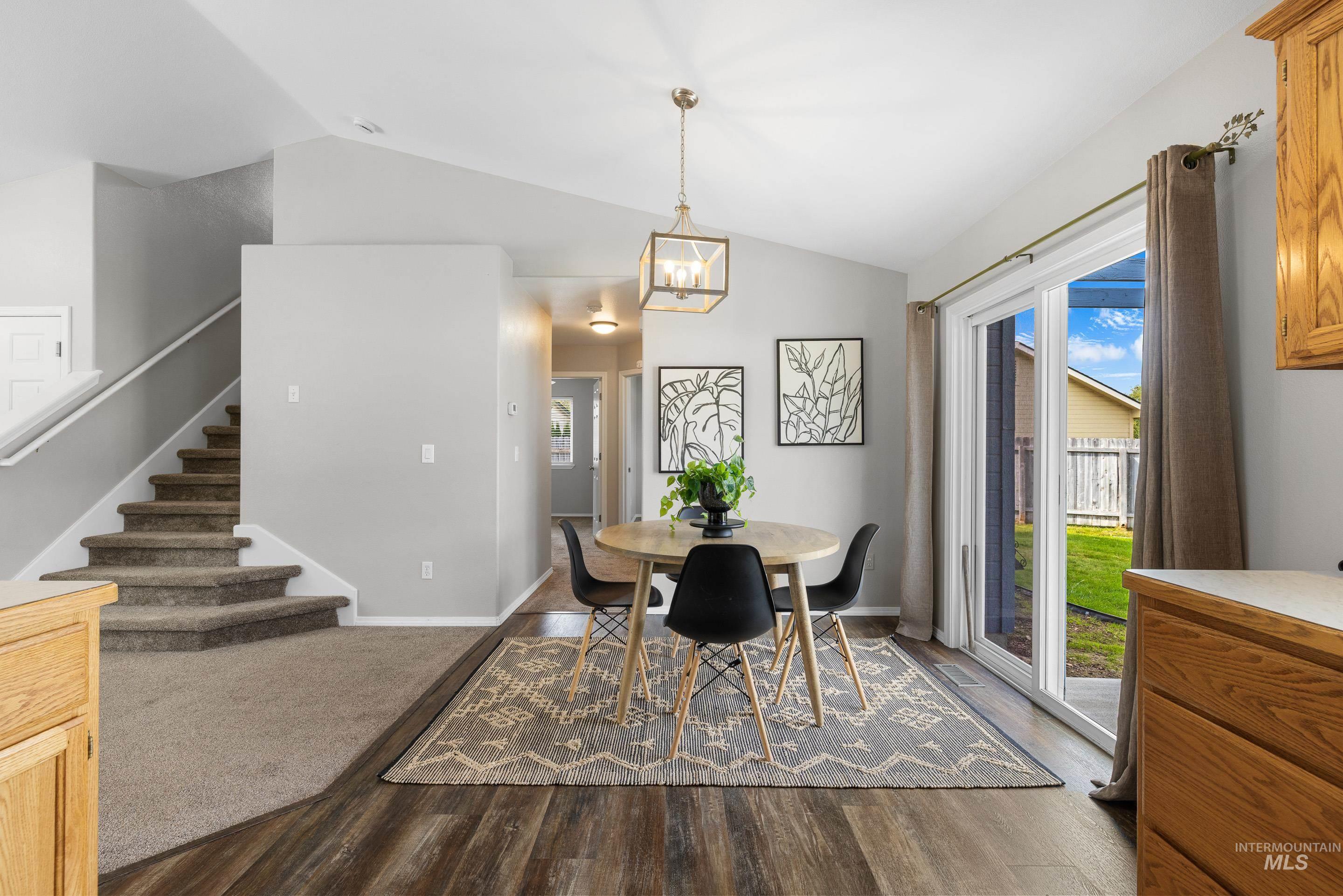 Dining area with stairs, lofted ceiling, and dark wood-type flooring