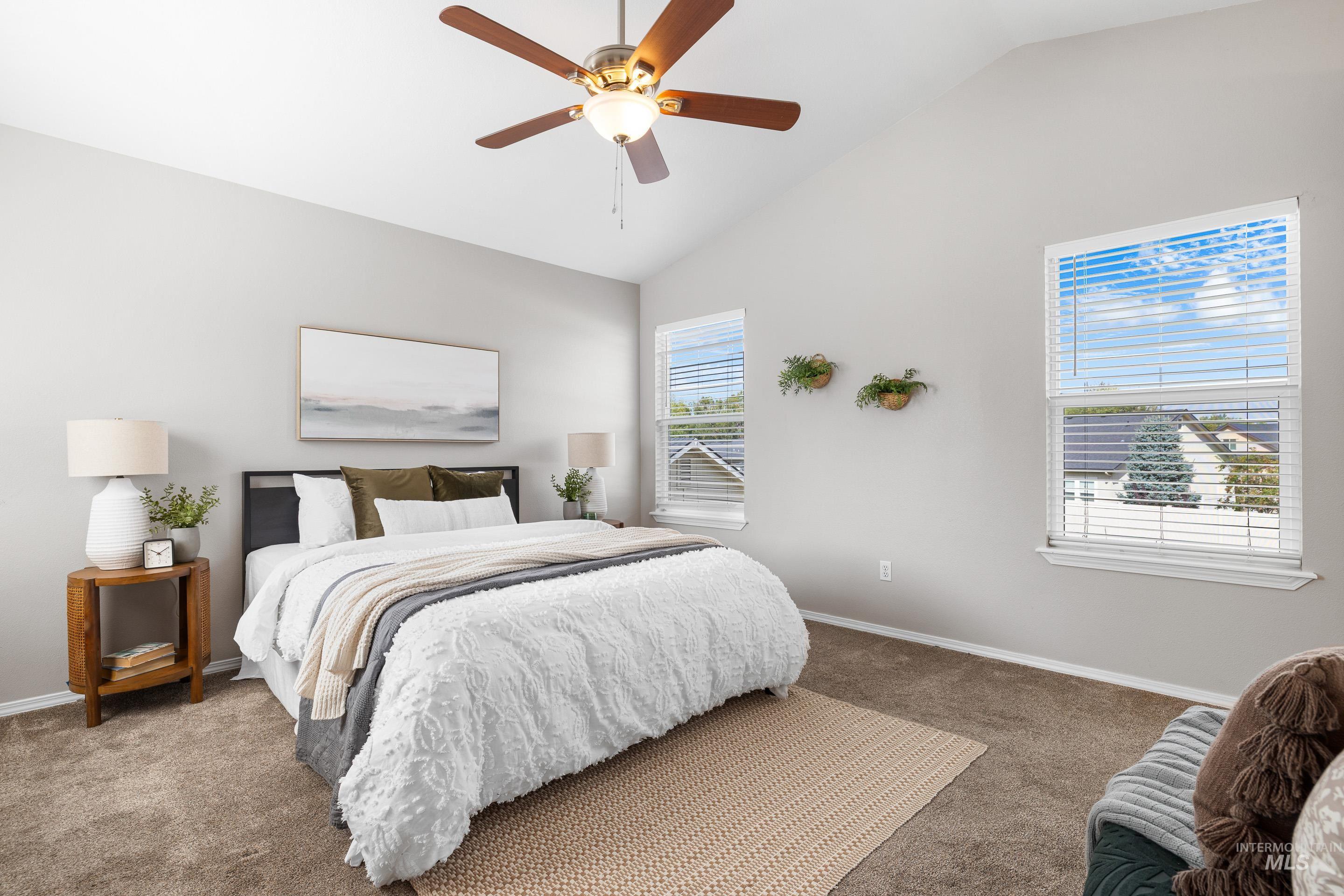 Carpeted bedroom with a ceiling fan and high vaulted ceiling