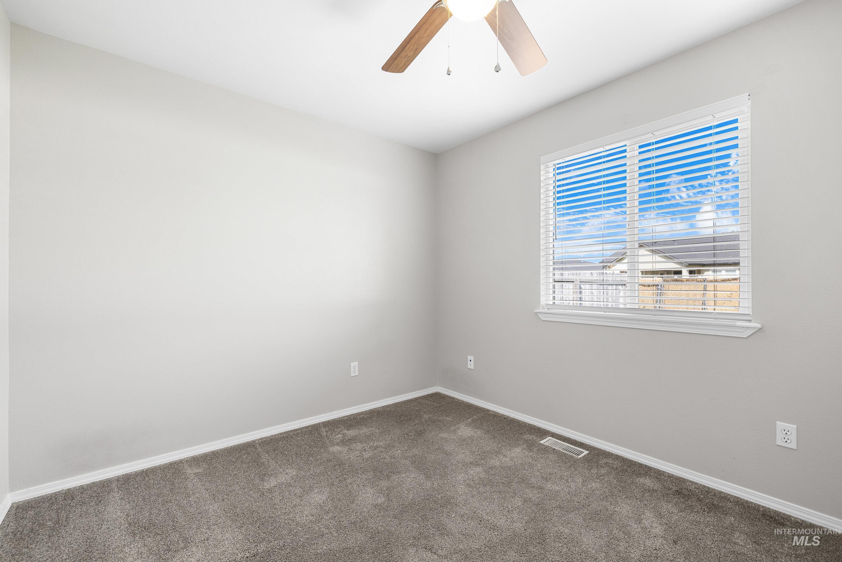 Carpeted spare room featuring baseboards and ceiling fan