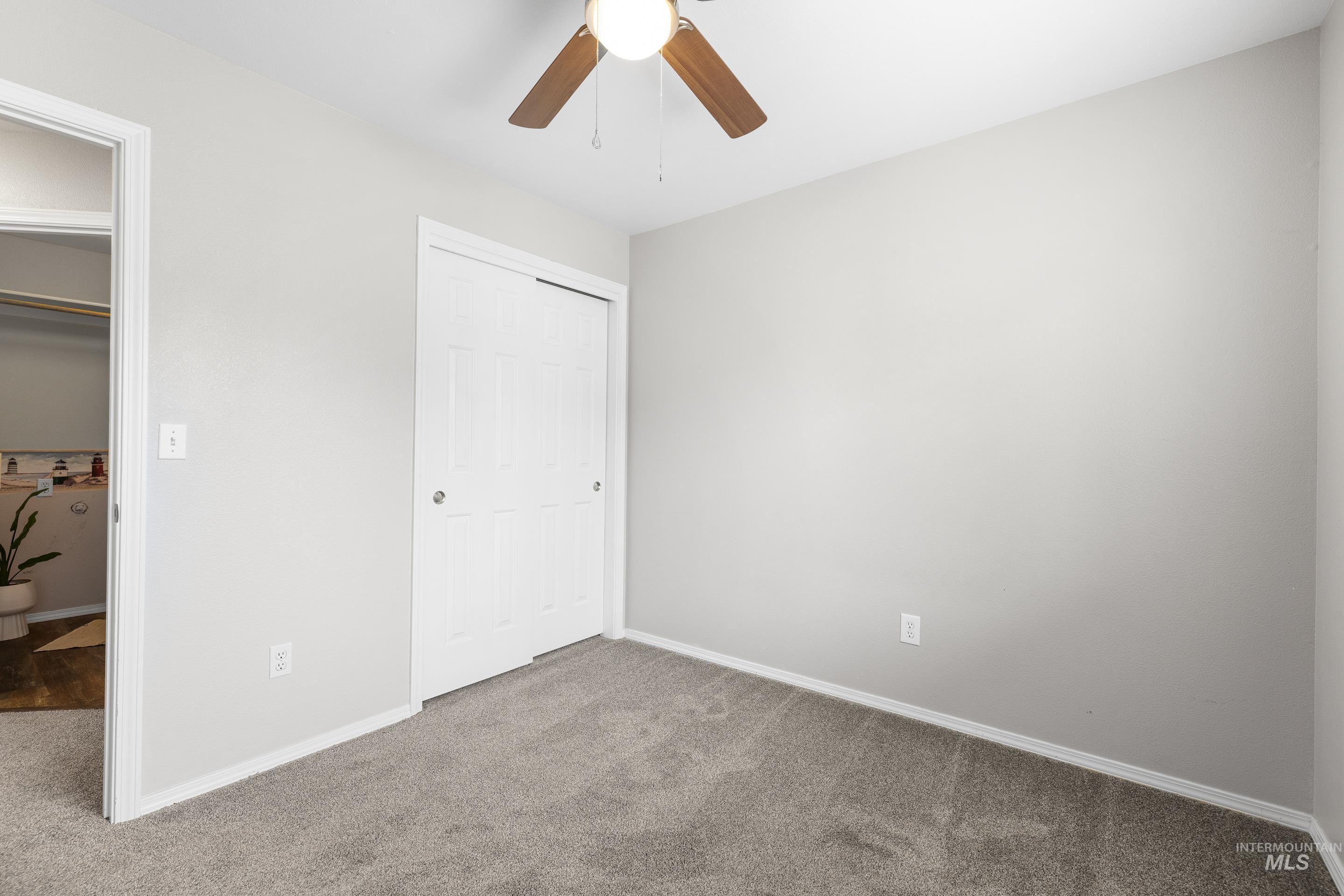 Unfurnished bedroom featuring carpet floors, a closet, and a ceiling fan