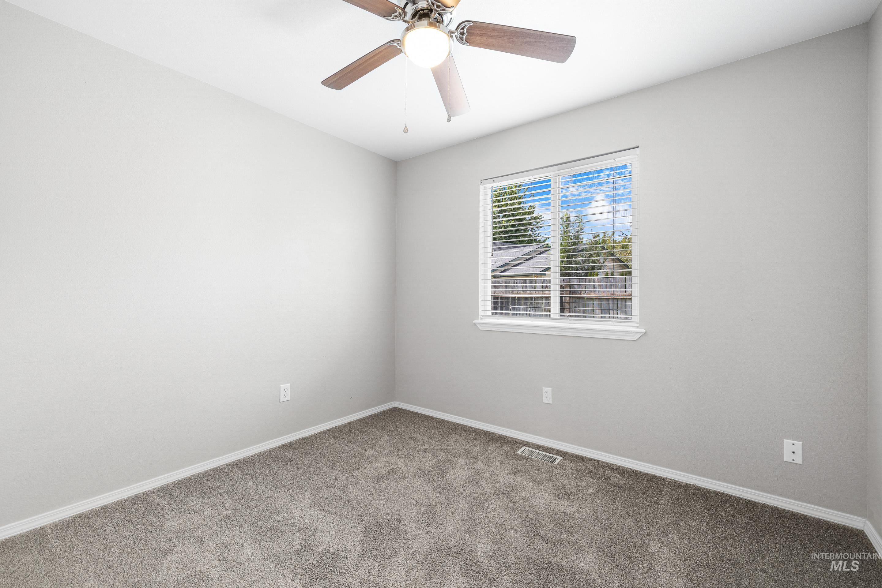 Empty room featuring carpet floors and a ceiling fan