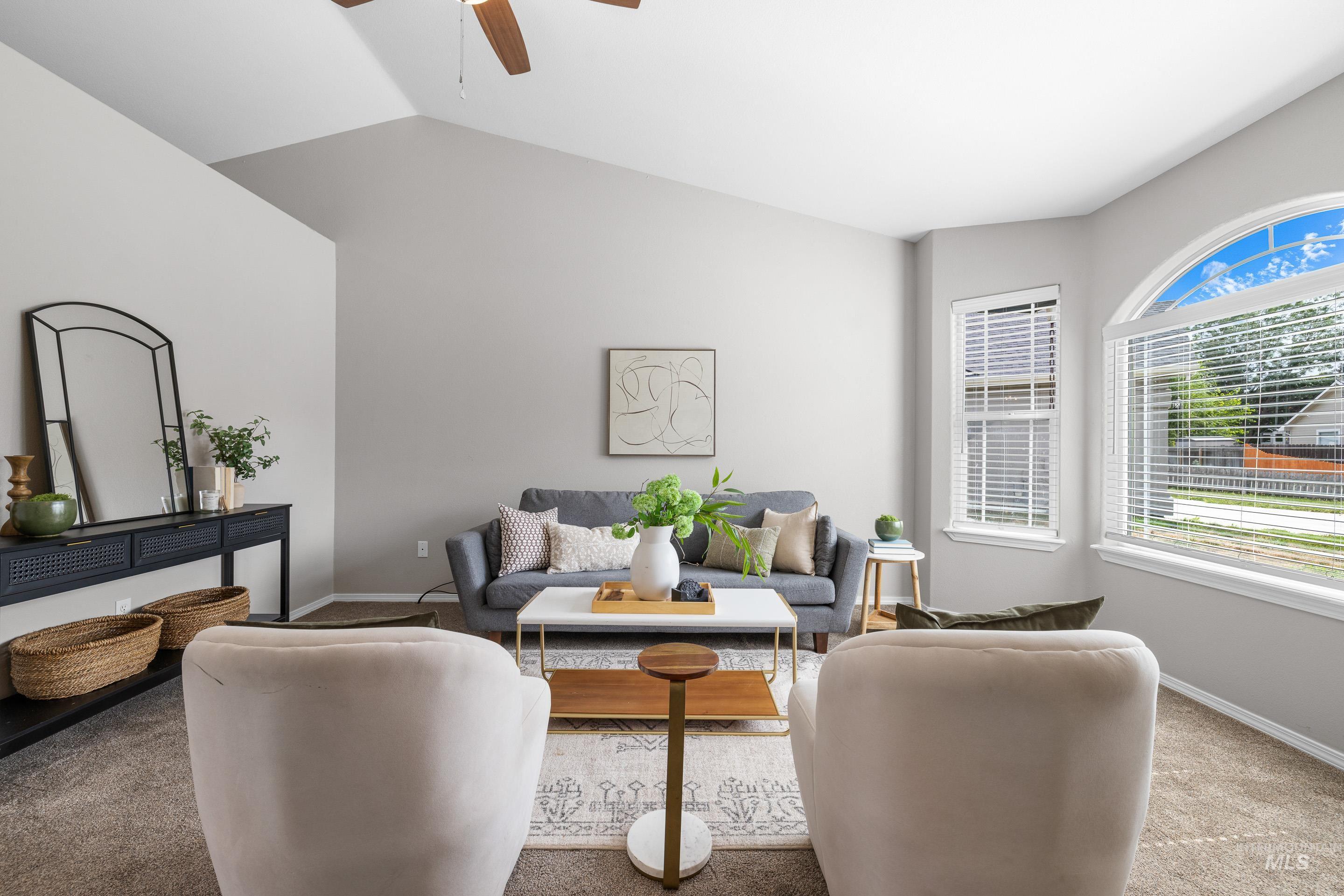 Carpeted living room featuring ceiling fan and vaulted ceiling