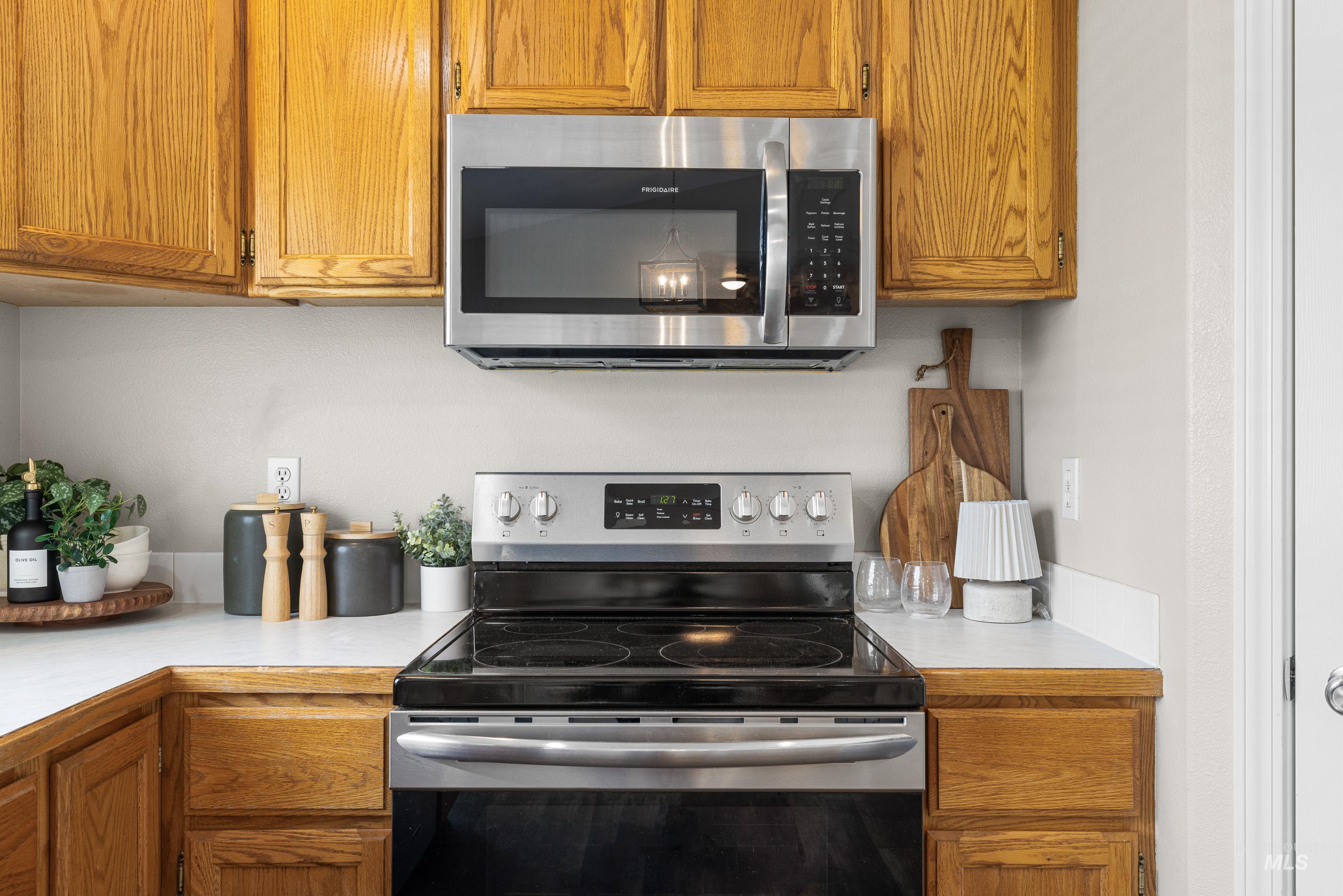 Kitchen with stainless steel appliances, light countertops, and brown cabinetry