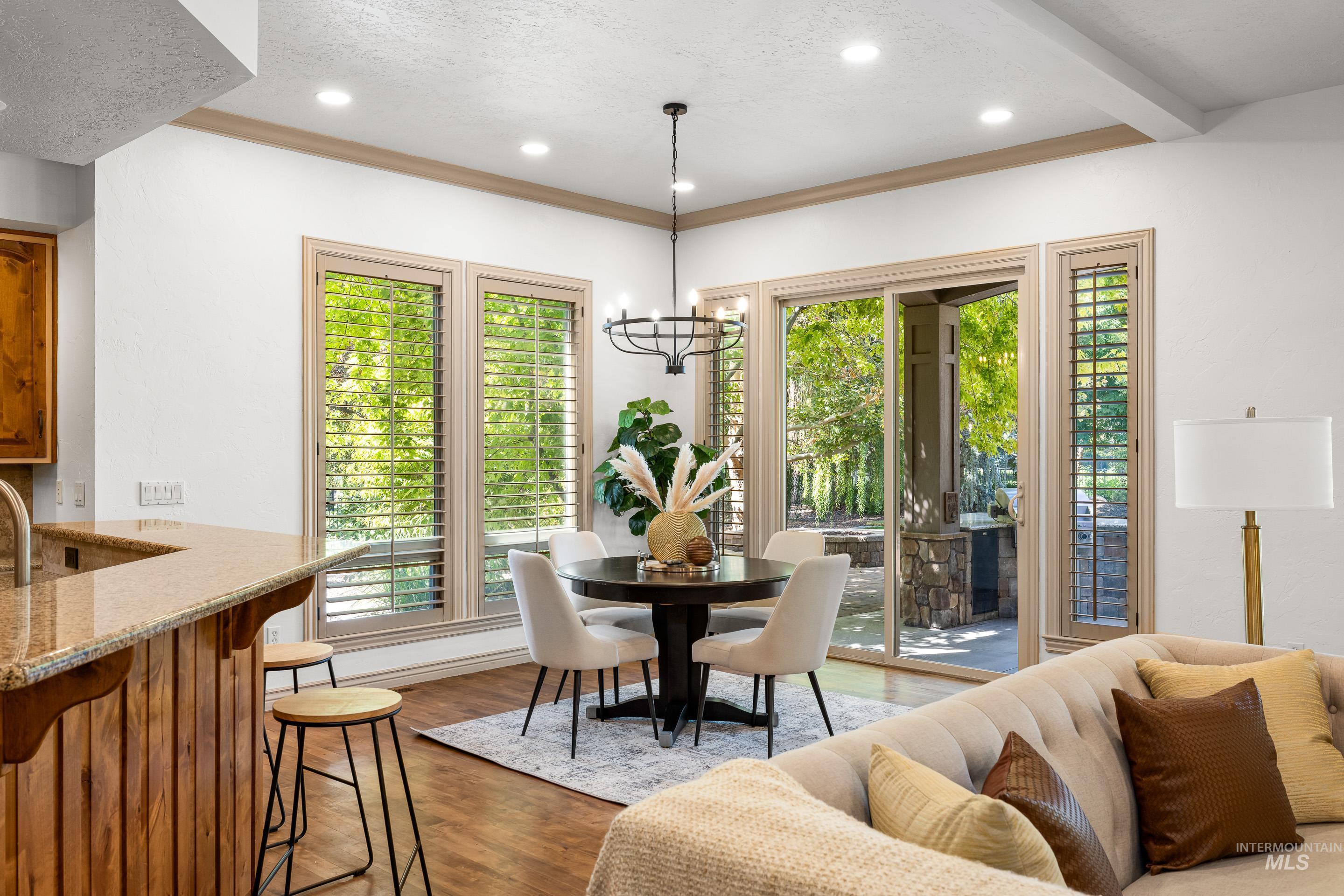 Dining area with wood finished floors, a chandelier, recessed lighting, ornamental molding, and a textured ceiling
