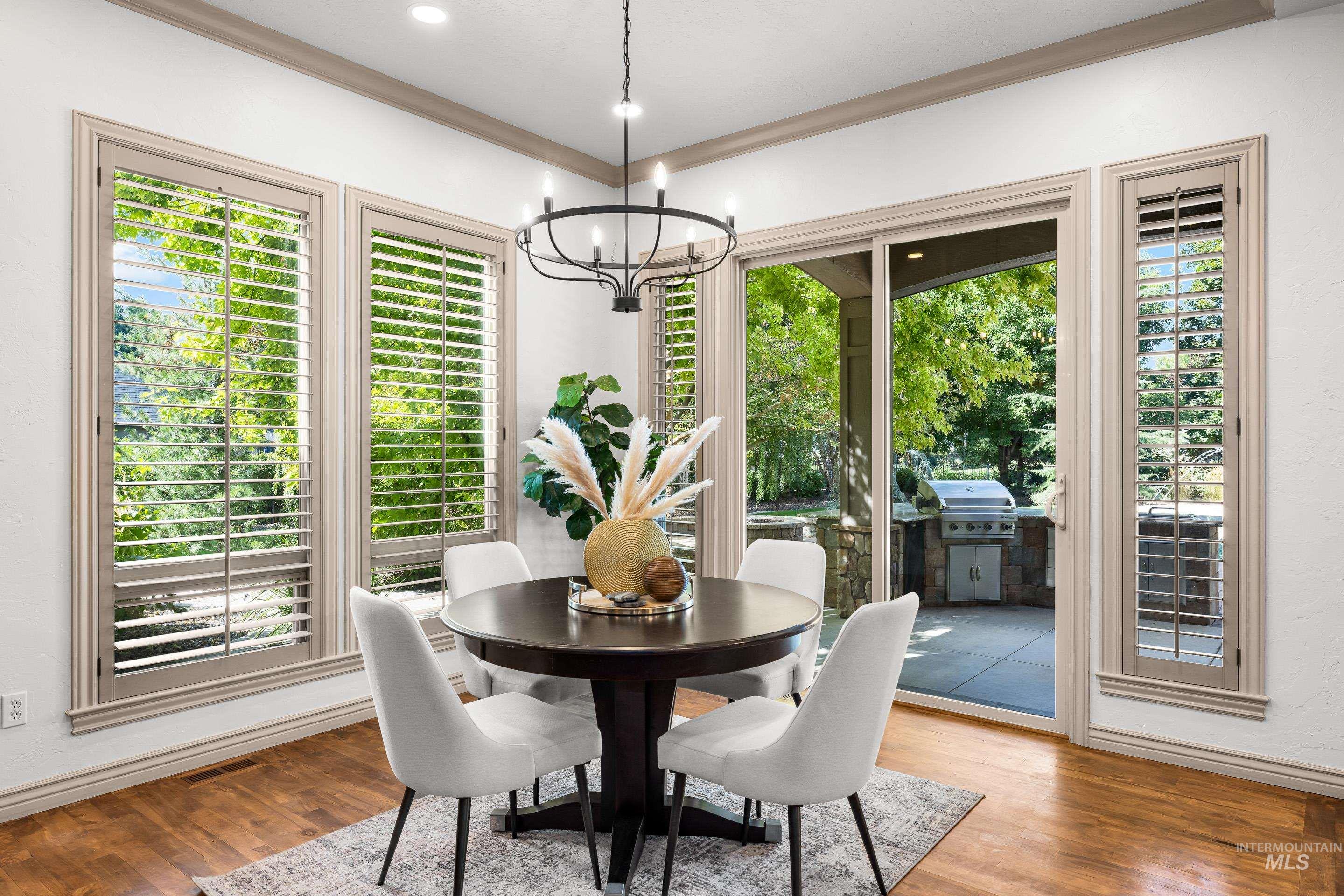 Dining room with wood finished floors, a chandelier, and crown molding