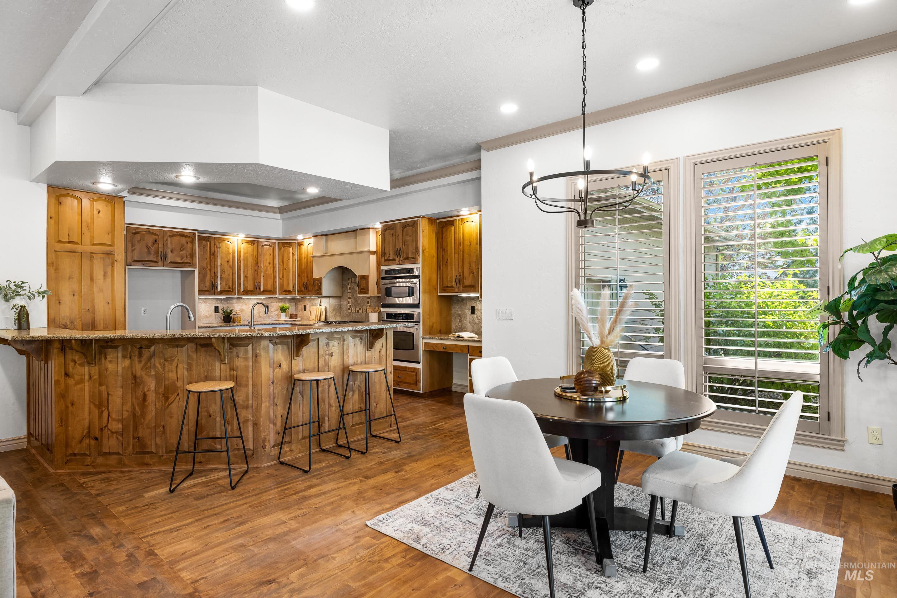 Dining room with dark wood-style flooring, a chandelier, recessed lighting, and ornamental molding