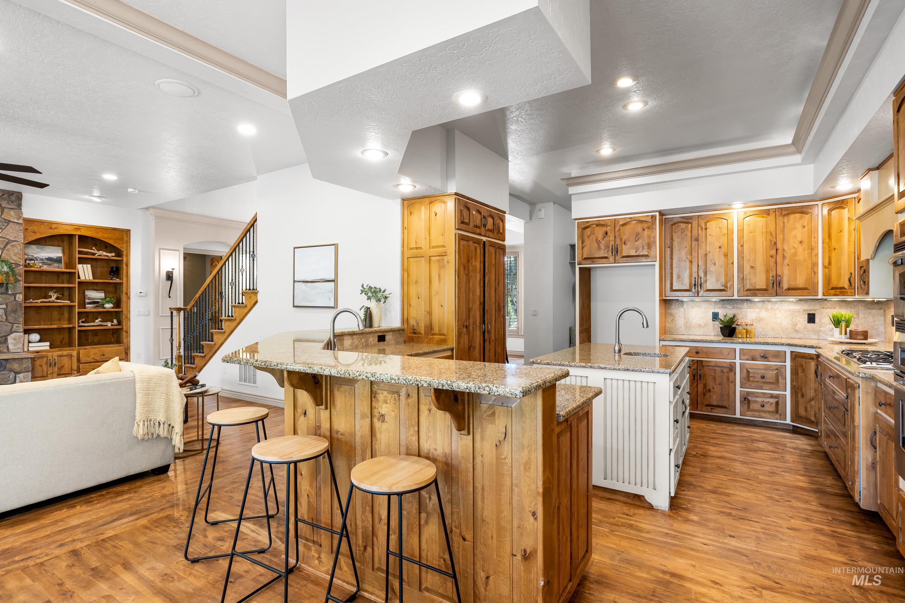 Kitchen featuring decorative backsplash, a breakfast bar area, light wood-type flooring, brown cabinets, and light stone counters