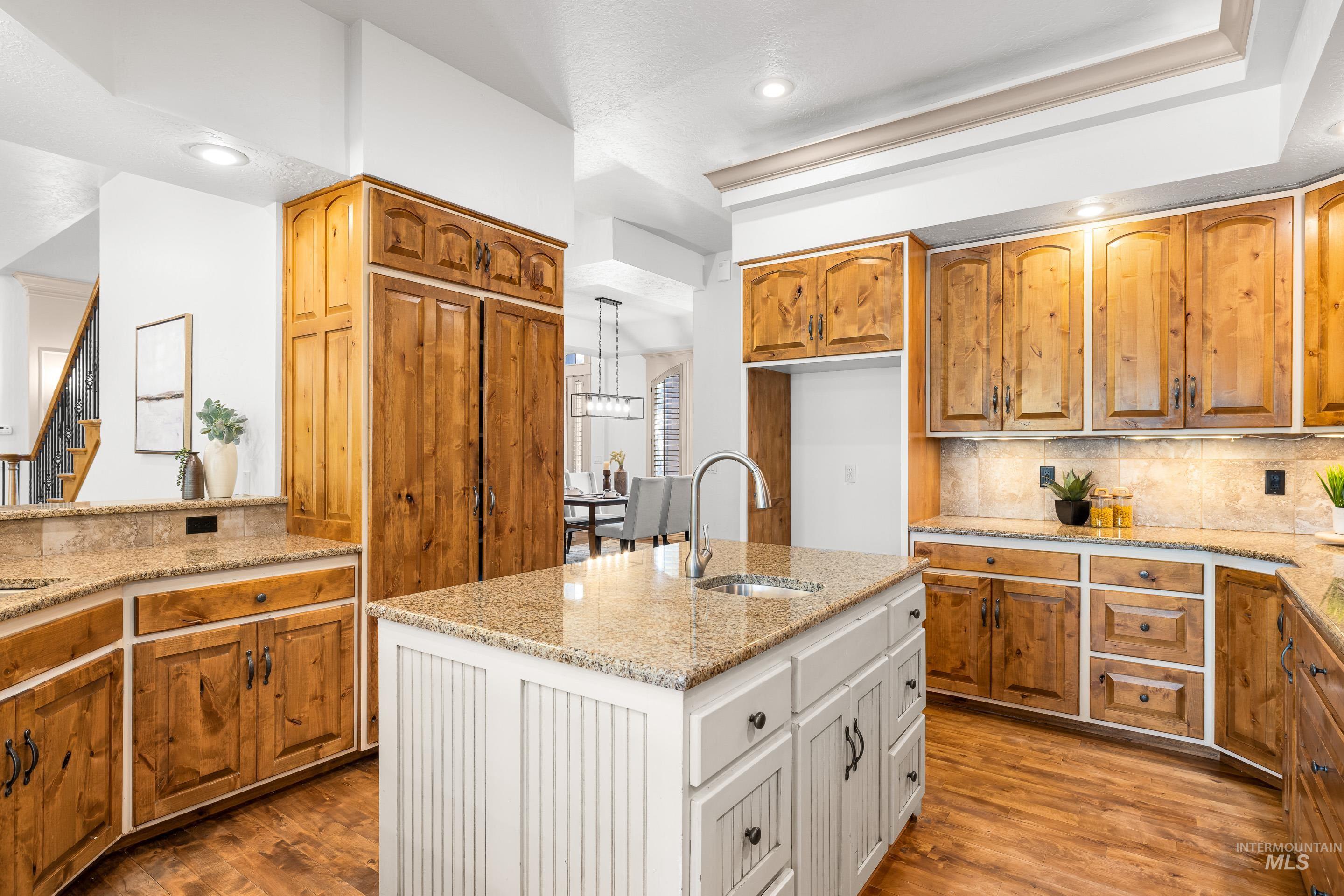 Kitchen featuring backsplash, white cabinetry, light stone countertops, and brown cabinets