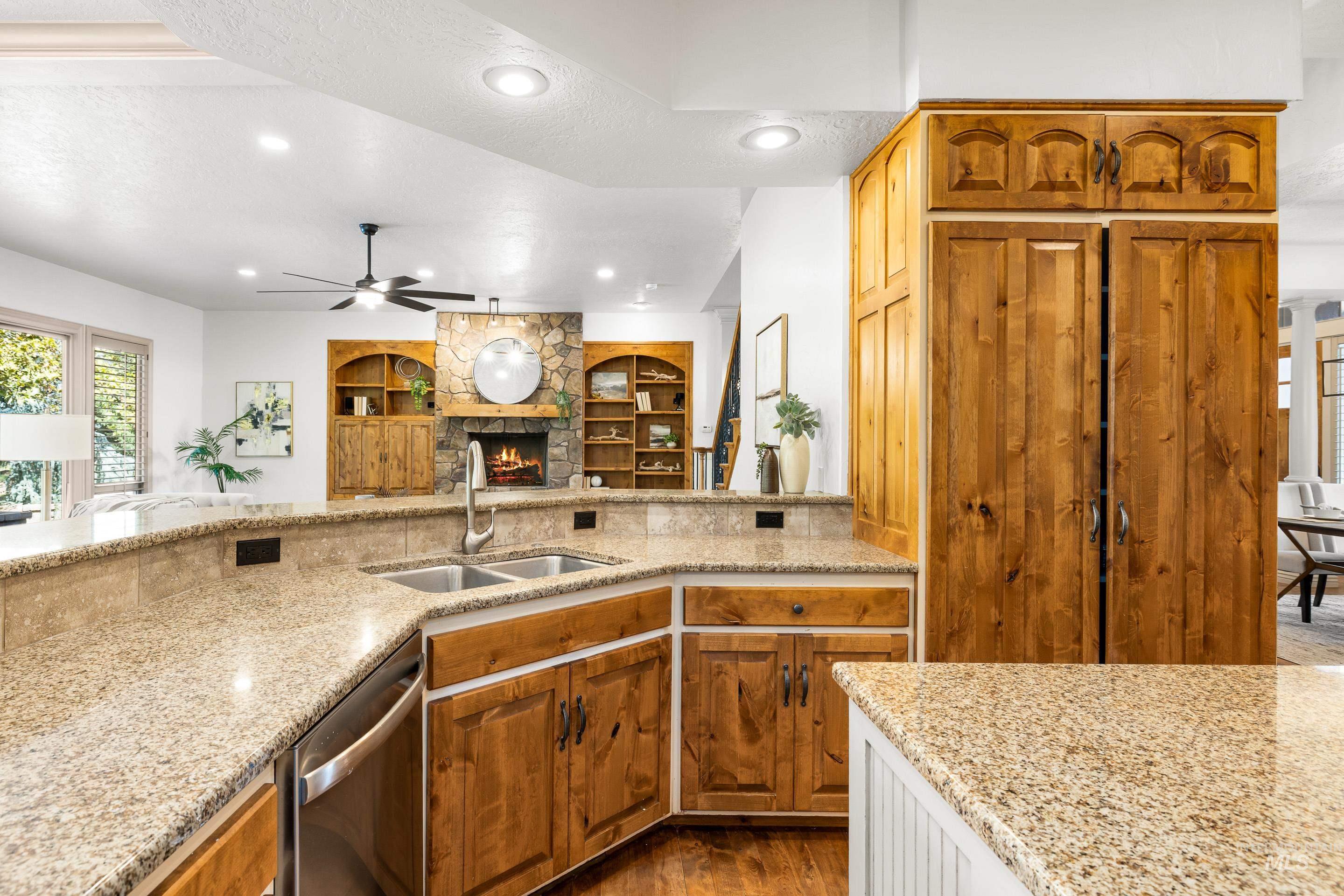 Kitchen with healthy amount of natural light, a textured ceiling, brown cabinetry, light stone countertops, and a fireplace